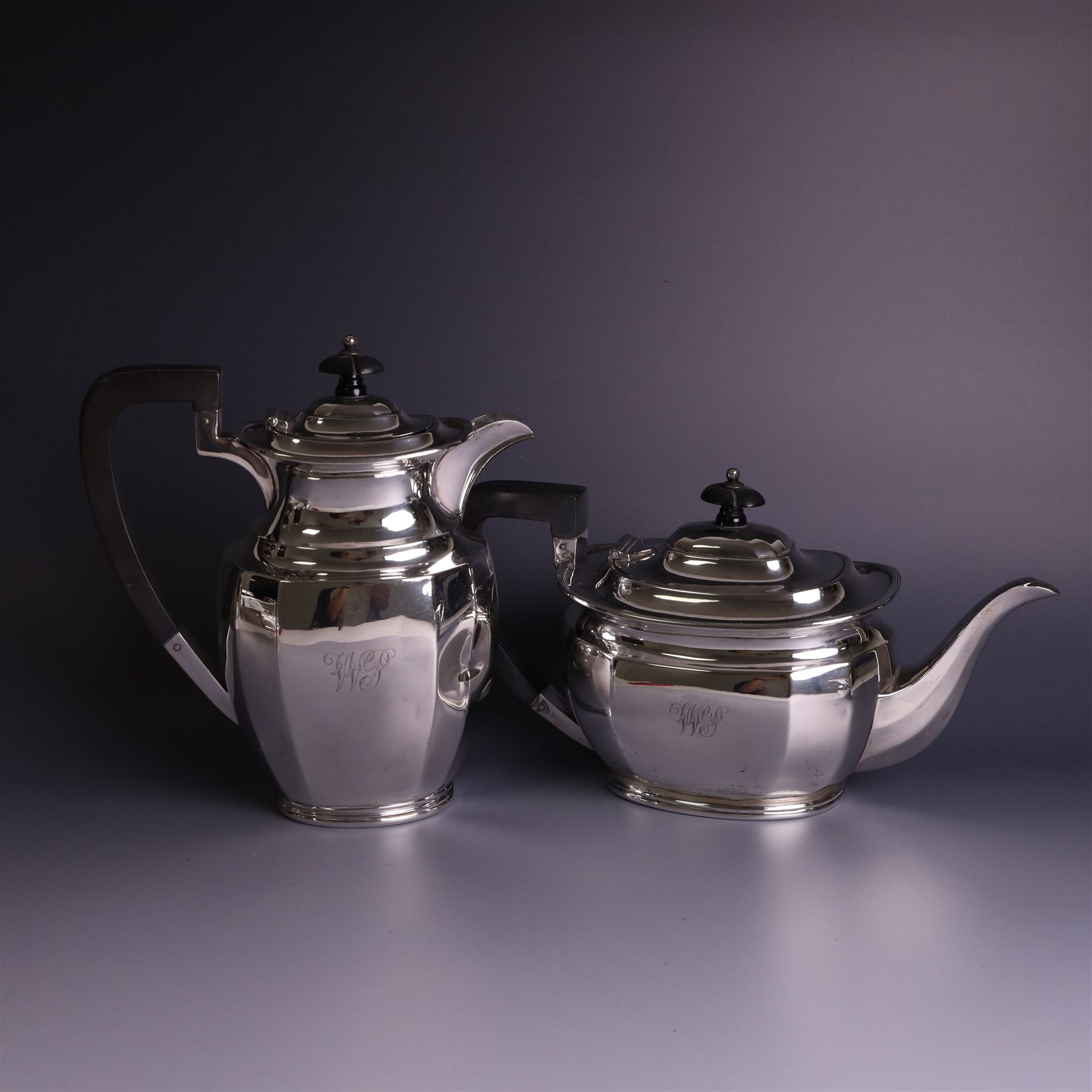 1930s silver four piece tea service, comprising teapot, hot water pot, sugar bowl and milk jug, each of part faceted oval form with engraved monogram to body, the teapot and hot water pot with Bakelite type handles and finials, hallmarked Atkin Brothers, Sheffield 1933