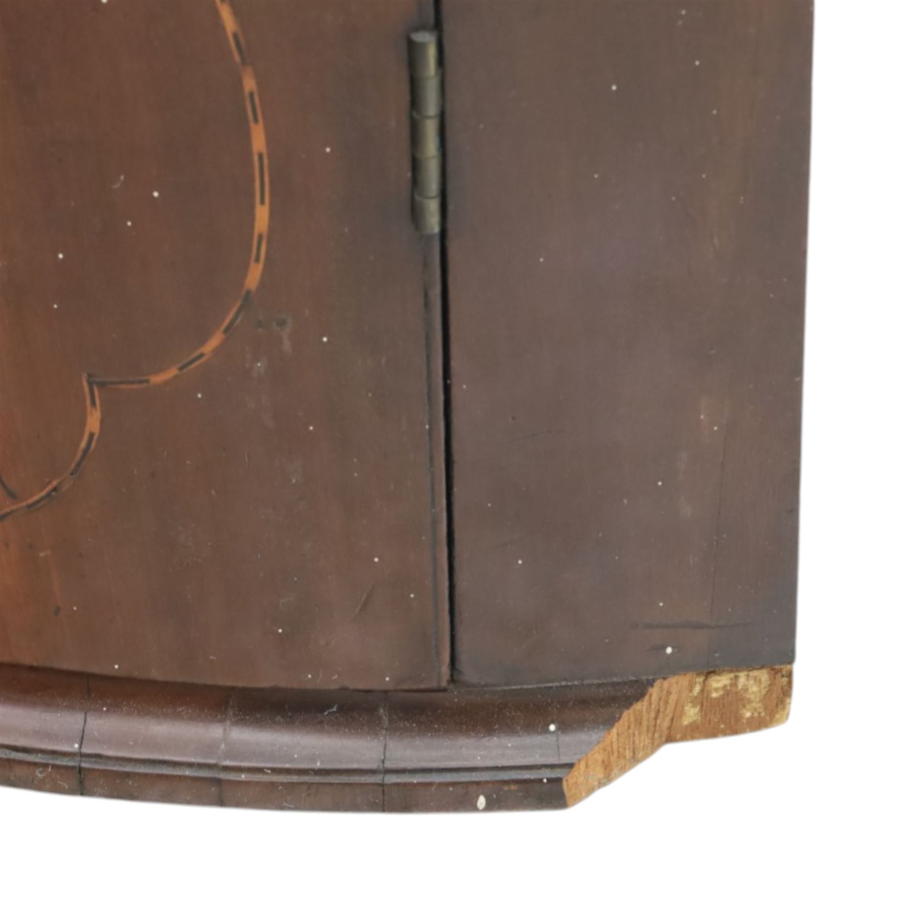 George III mahogany bow-front corner cupboard, projecting moulded cornice over satinwood inlaid frieze with geometric crossbanding, enclosed by twin shaped panel doors with line inlay and ornate brass escutcheon plates, painted interior fitted with shaped shelves, on moulded plinth base