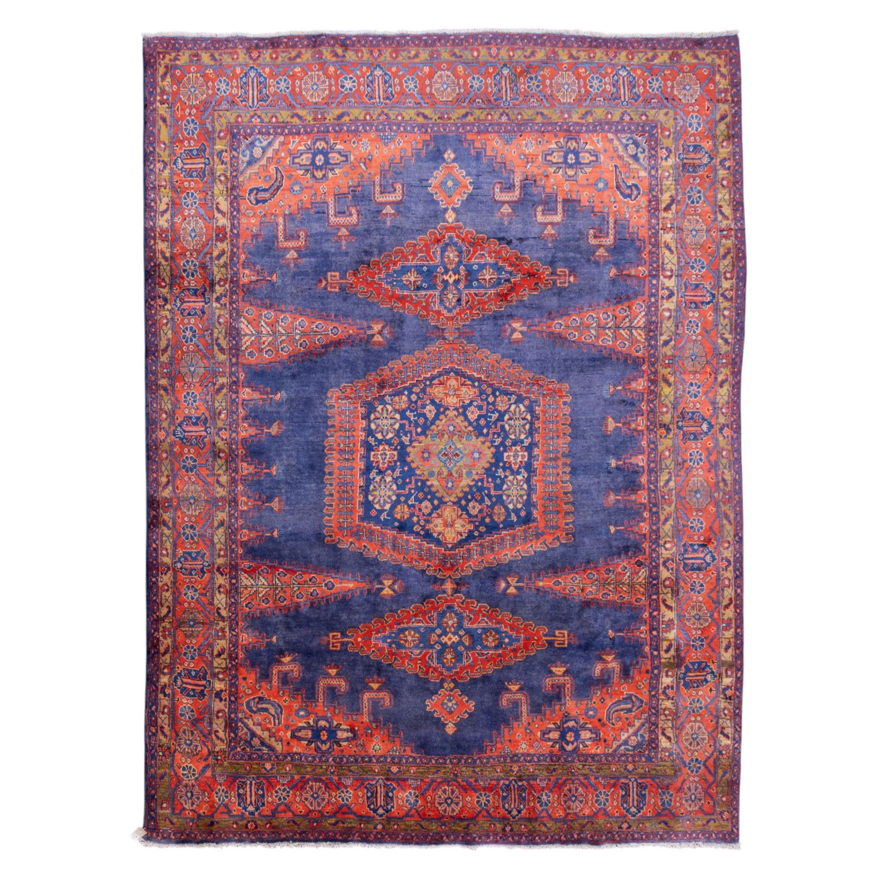 Central Persian Veis hand-knotted carpet, deep blue indigo field with central stepped lozenge medallion filled with stylized floral and geometric motifs, flanked by further angular medallions and tribal devices, edges with articulated and serrated hooked forms within a wide geometric border with repeating stylized floral motifs and multiple guard borders, in madder red, indigo blue, ivory, olive green, with cotton fringe ends