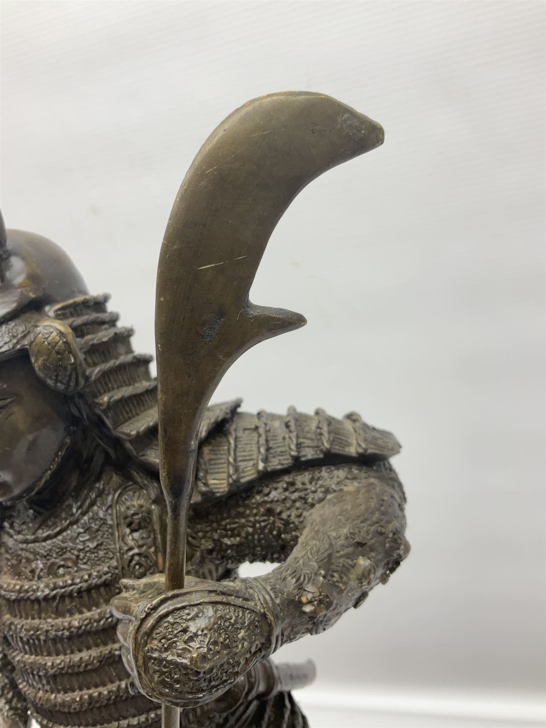 Bronze figure of a samurai standing wearing armour and holding a naginata, upon a rocky base, H48cm