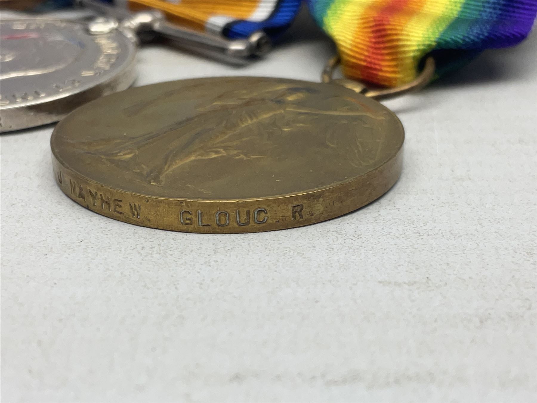 WW1 KIA group of three medals comprising British War Medal, 1914-15 Star and Victory Medal awarded to 9069 Cpl. J. Mayhew Glouc. R.; with ribbons; displayed on modern bar, and photograph of recipient in uniform; some biographical details
