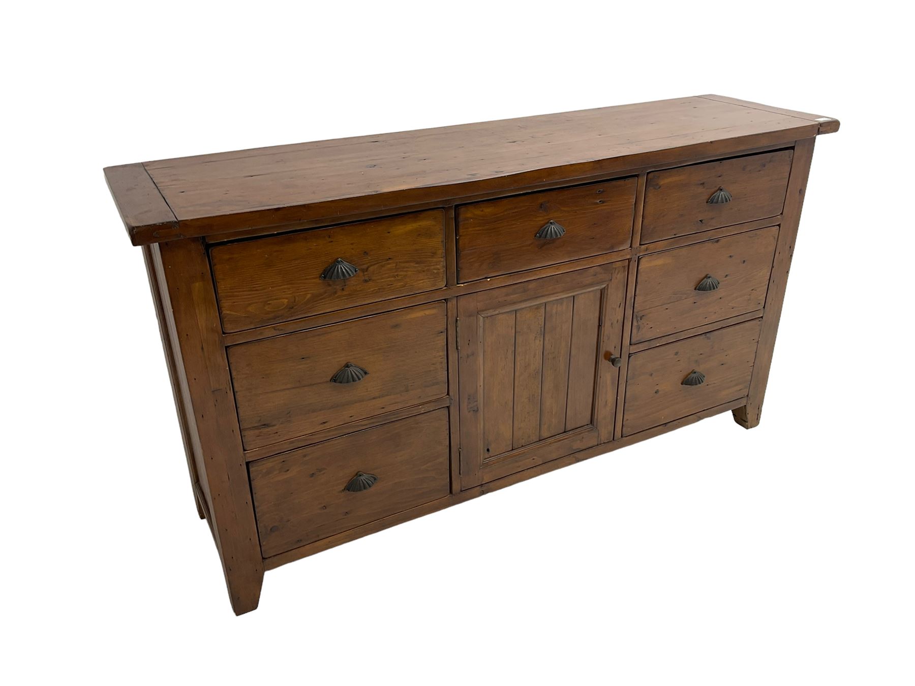 Stained pine rustic sideboard, rectangular top over seven drawers and single panelled cupboard, fitted with shell handles