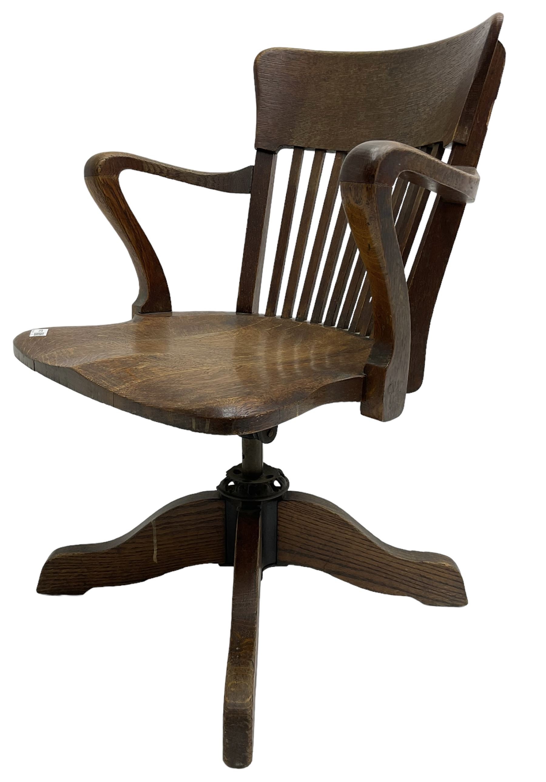 Early 20th century swivel office desk chair, shaped bar back over vertical rails, dished seat, on four splayed supports