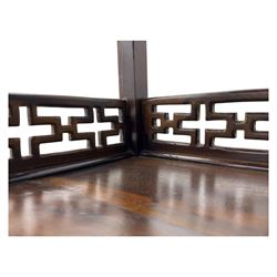 Early 20th century Chinese hardwood display étagère bookcase, the rectangular open tiered frame with pierced frieze and geometric openwork gallery to each shelf, fitted with two short drawers carved with stylised lotus motifs, supported on square uprights with pierced apron and integral gallery rails