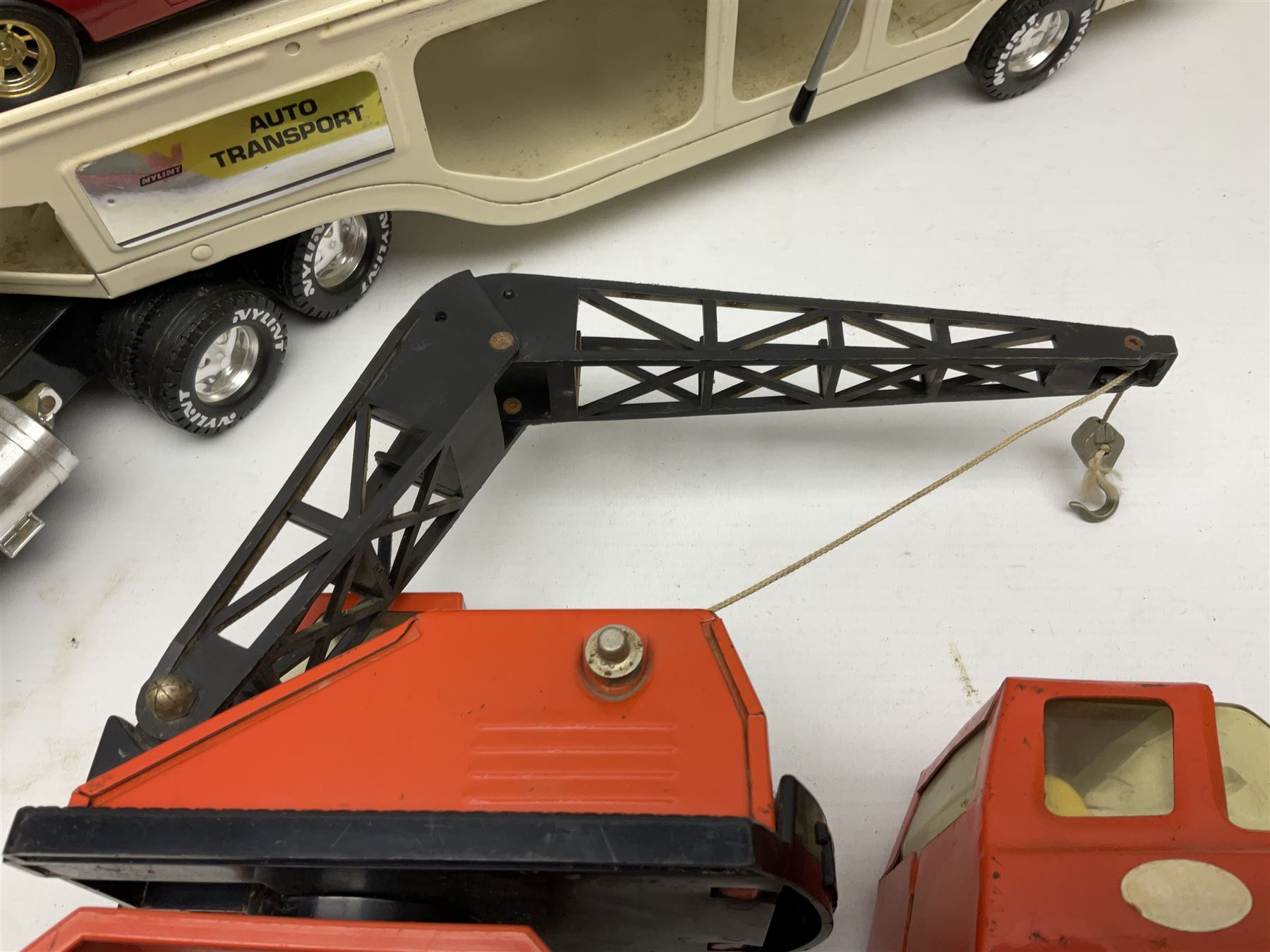 American Nylint large scale tin-plate car transporter L59cm carrying a Testor Toys plastic car; Tonka tin-plate mobile crane; boxed Sarony Cigarettes tin-plate roulette game with rules; and Japanese style tin-plate box, the lid inset with a revolving poker dice game (4)