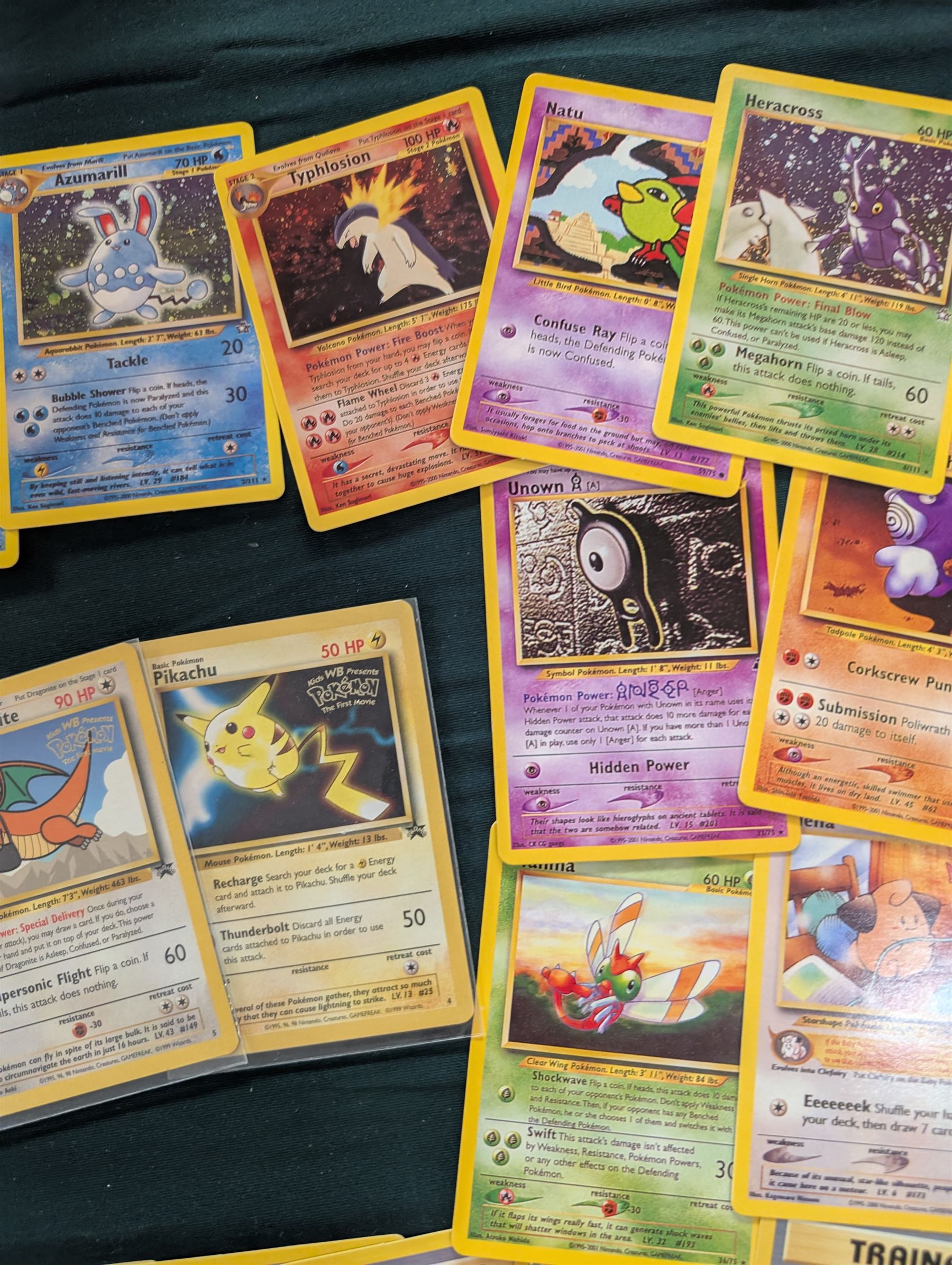 Collection of Pokemon TGC trading cards, including two WB First Movie Black Star promo cards Pikachu no. 4 and Dragonite no. 5, two Ancient Mew Black Star holo promo cards, Gym Challenge Giovanni's Persian 8/132 holo and a small collection WOTC, Neo Discovery and Neo Genesis cards, together with thirty four Bandai Carddass Pokemon cards, including prism Charizard no. 186 and Pokemon Topps cards including holo examples 