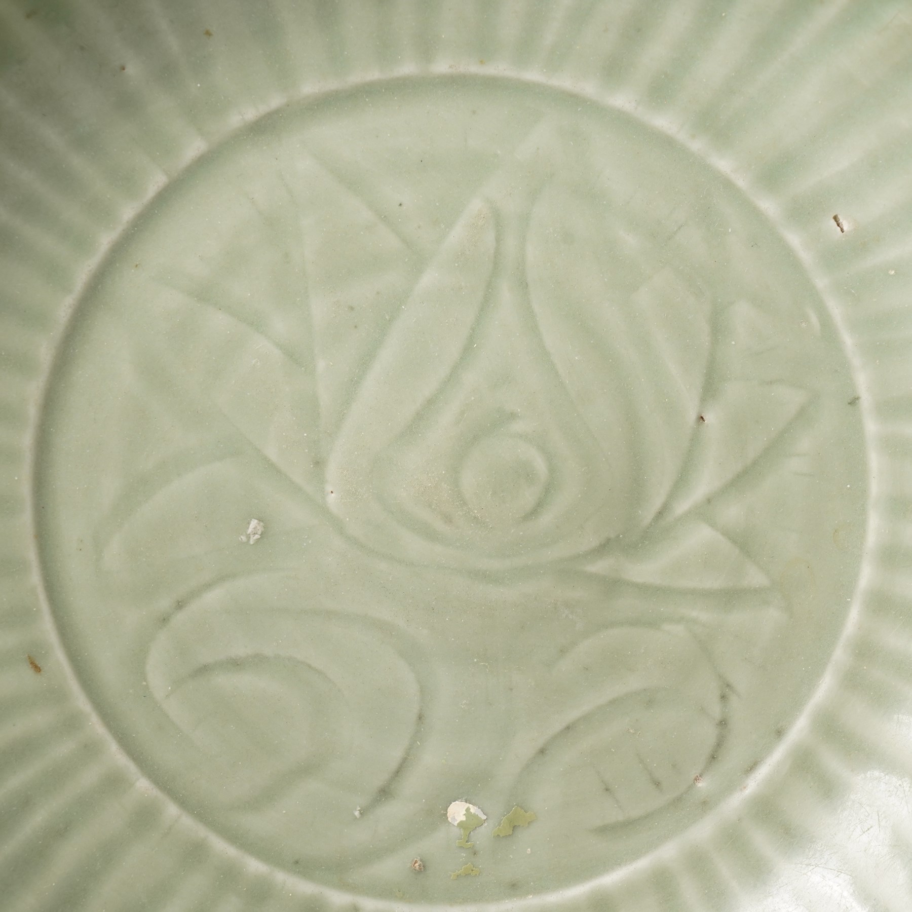 Chinese Ming dynasty Longquan celadon dish, the base carved with a lotus within a ribbed surround D35cm