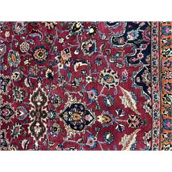 Persian Meshed carpet, plum ground and decorated with stylised flower heads and interlacing foliate, large central stylised medallion with orange detail, the orange mirrored in the five band border decorated with scrolling floral design, signature panel to end 
