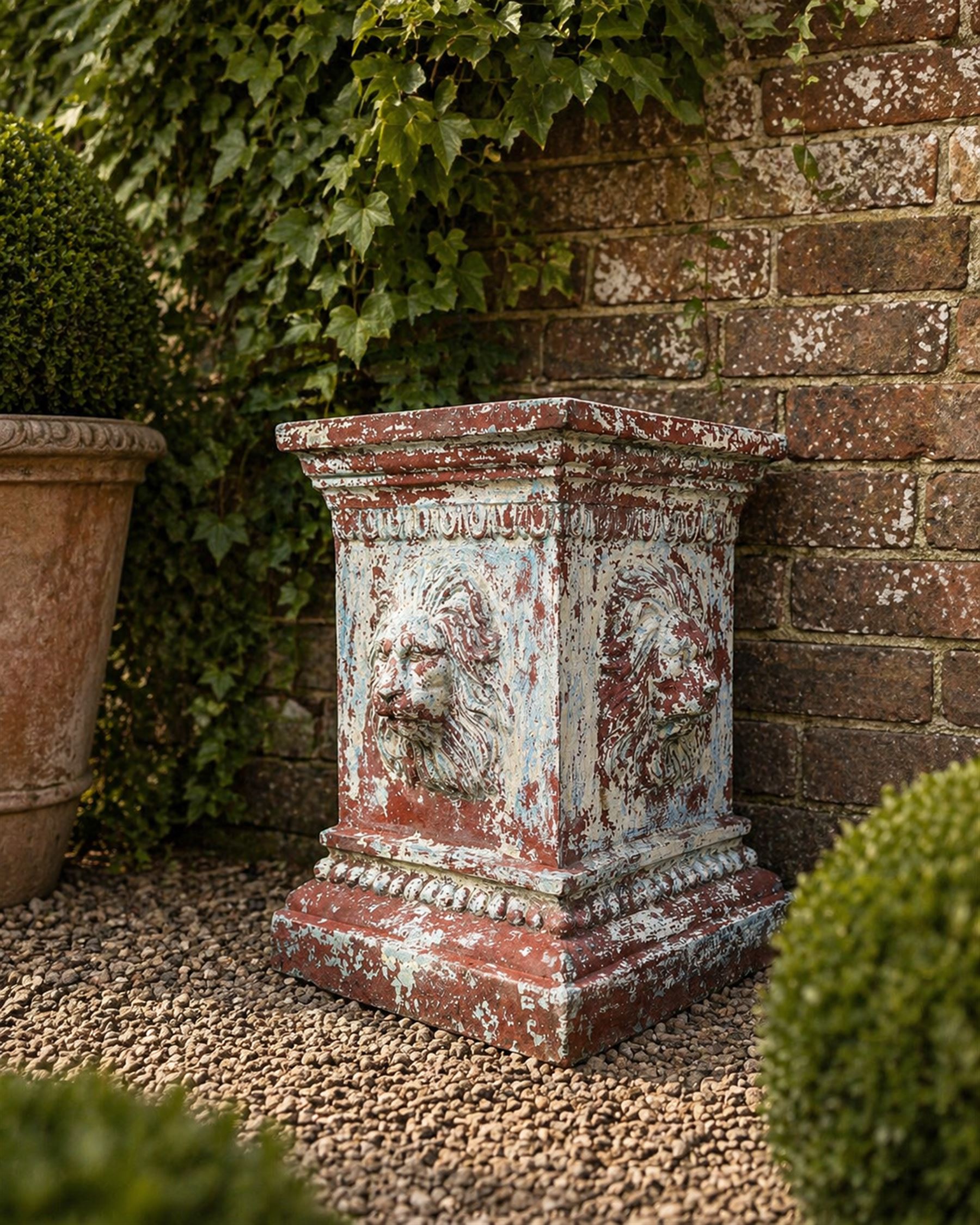 Early 20th century terracotta pedestal, square form with egg and dart detail, four lions masks to either side, finished in distressed cream paint