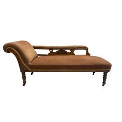 Late 19th century walnut framed chaise longue, scrolled back with pierced and carved arm rail, sprung seat upholstered in dark coral fabric, raised on turned supports with castors