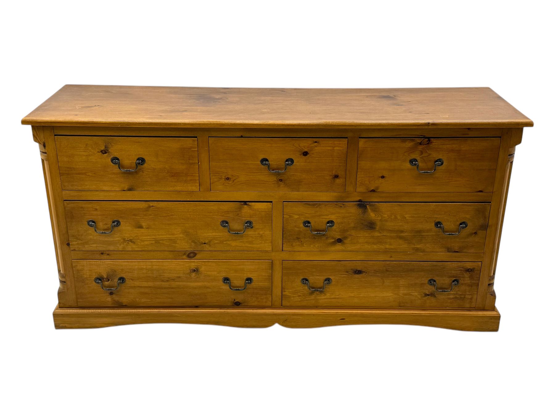 Pine dresser, rectangular top above seven drawers, with two smaller drawers over five larger drawers, all fitted with cast metal handles, raised on a shaped plinth base

