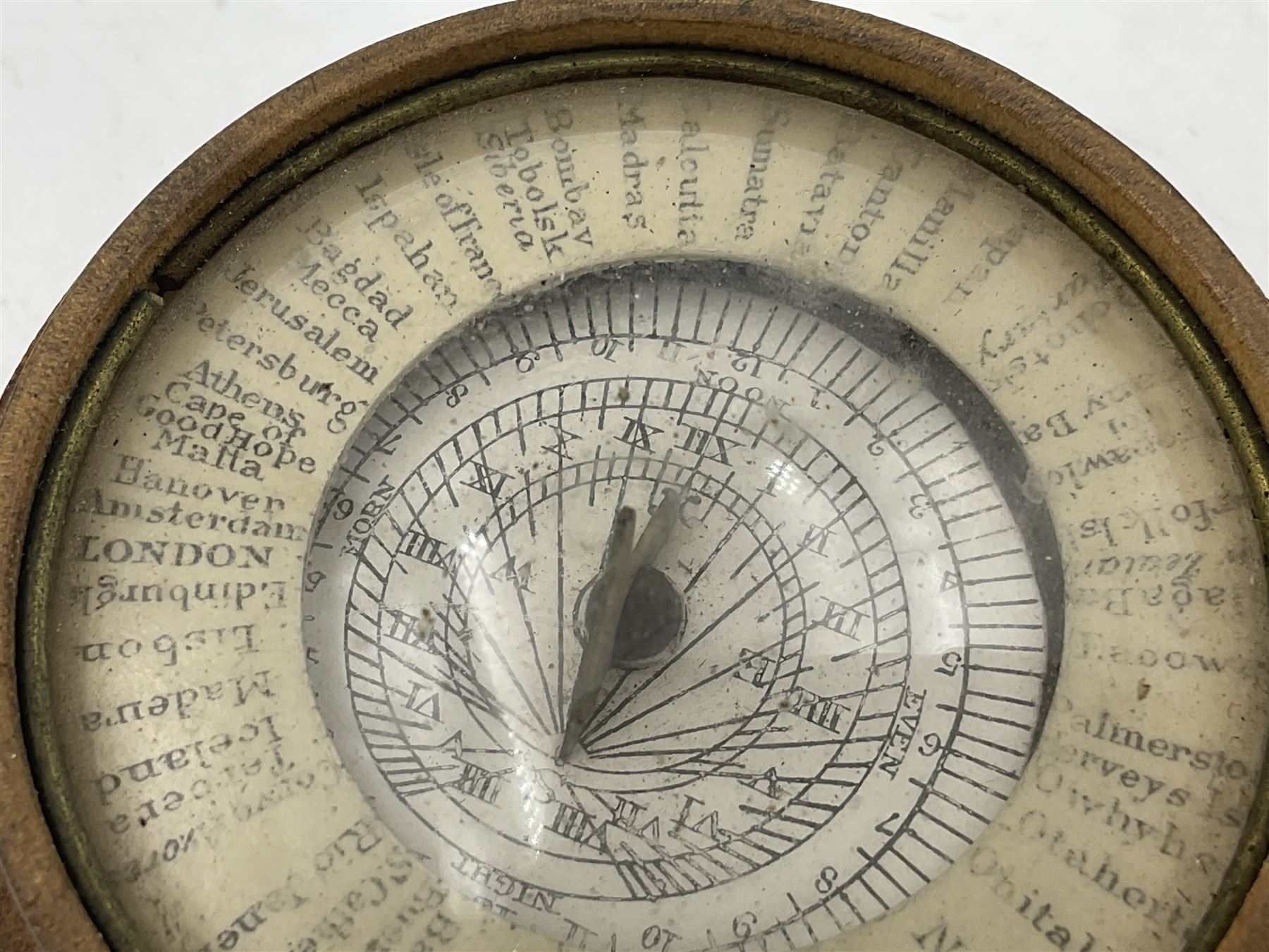 19th century pocket sundial compass pantochronometer, central sun dial pivoting with angled gnomon, within a broad enamelled band, listing world cities, paper calendar label to cover