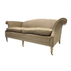 Traditional three seat sofa, curved back over scrolled arms, upholstered in crushed beige fabric with matching loose cushions, on turned front supports with brass and ceramic castors, together with matching footstool