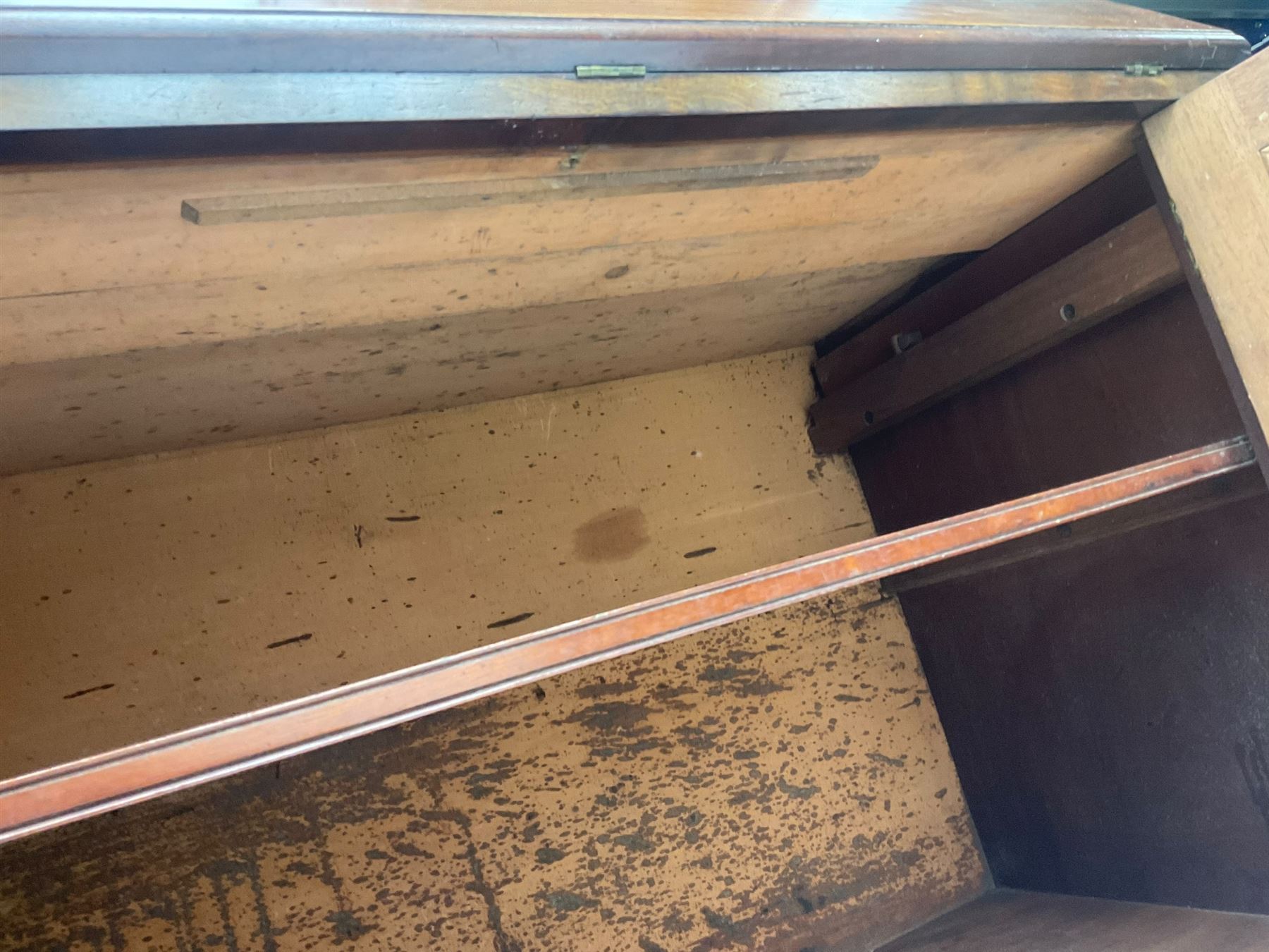 Early 19th century figured mahogany bureau bookcase, projecting splay moulded cornice over three adjustable shelves enclosed by two glazed doors, fall front revealing pigeonholes, cupboard and drawers, pull-out strays with scroll carved terminals, double cupboard with two panelled doors, on turned feet 