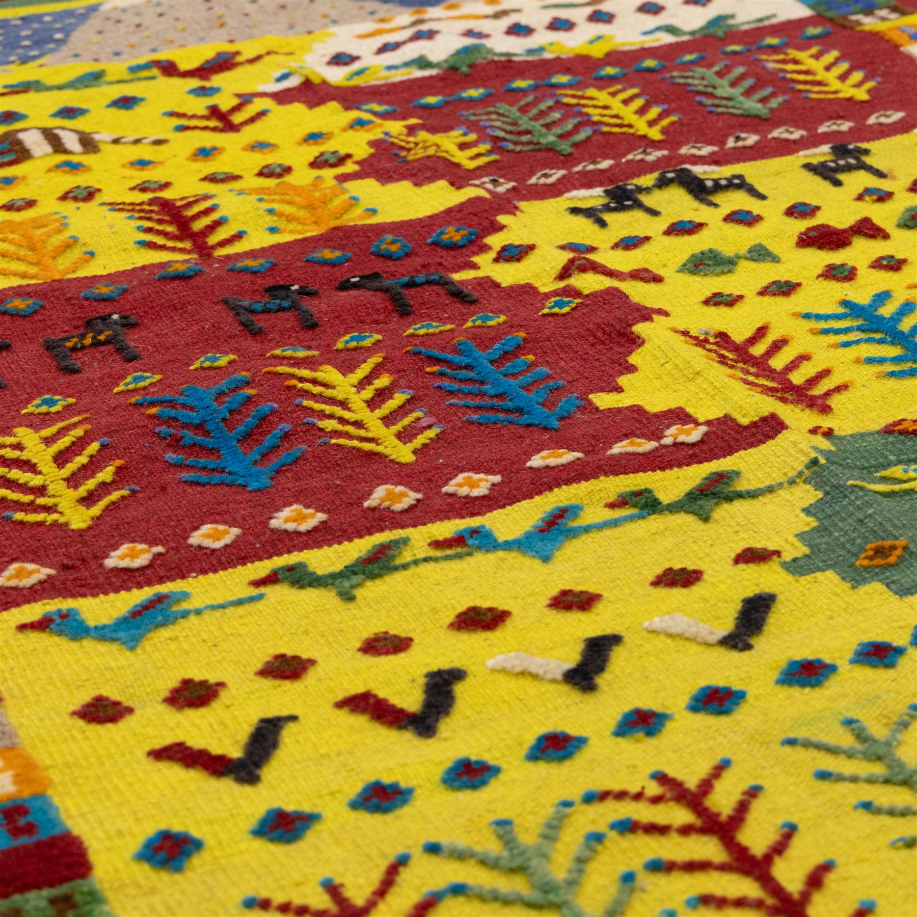 South West Persian Qashqai flatweave kilim, field arranged in bold horizontal bands of saffron yellow, madder red and deep green, decorated stylized tribal motifs including birds, animals, fish and schematic tree devices, composition arranged in a stepped asymmetrical format, with fringe ends 
