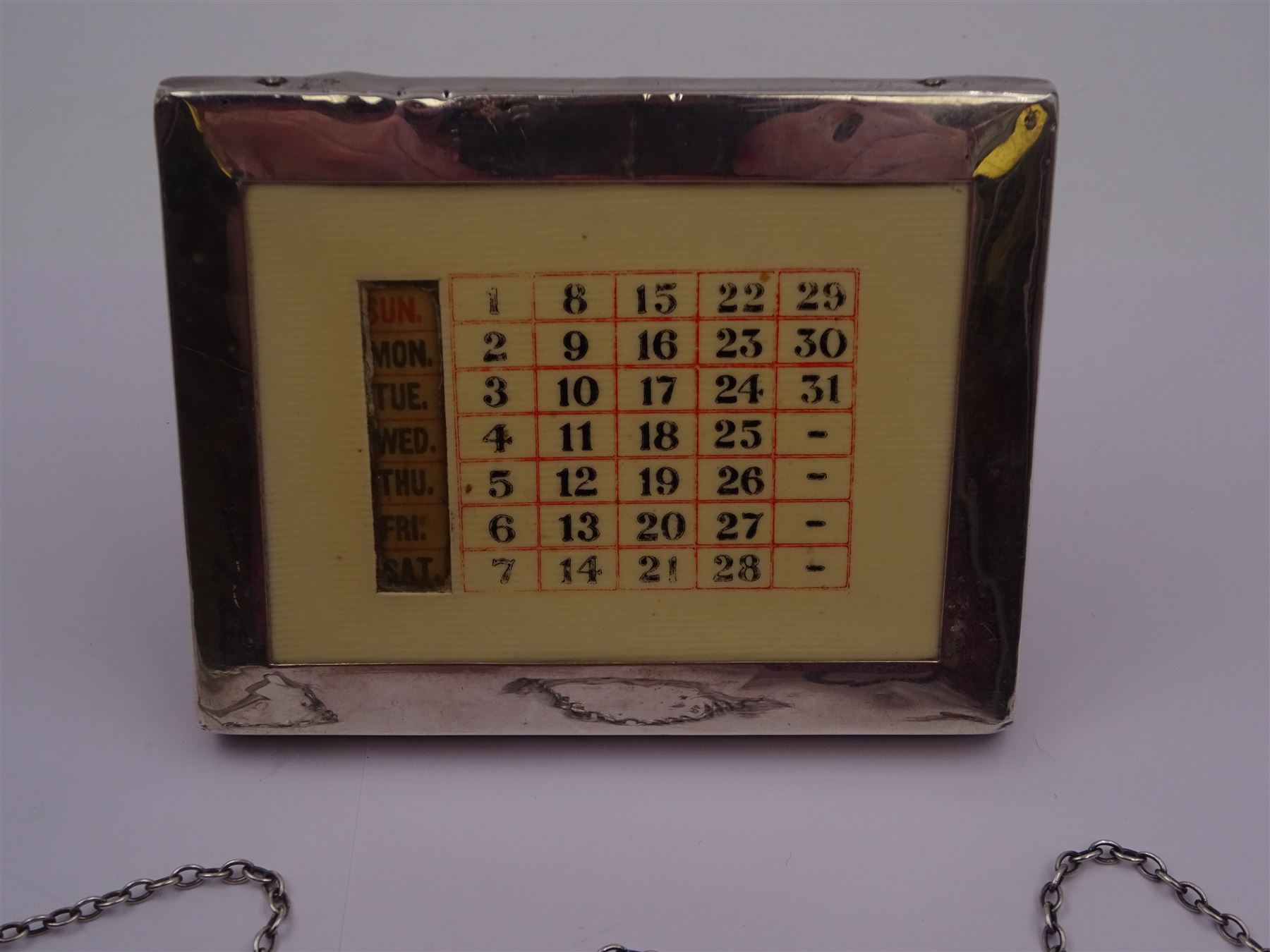 1920s silver mounted perpetual desk calendar, printed in red and black on an ivorine ground, hallmarked Charles S Green & Co Ltd, Birmingham 1925, with wooden easel style support verso, together with a set of three modern silver decanter labels, with cut-out lettering for gin, whisky and vodka, hallmarked London 1982, maker JKM, calendar H8.4cm