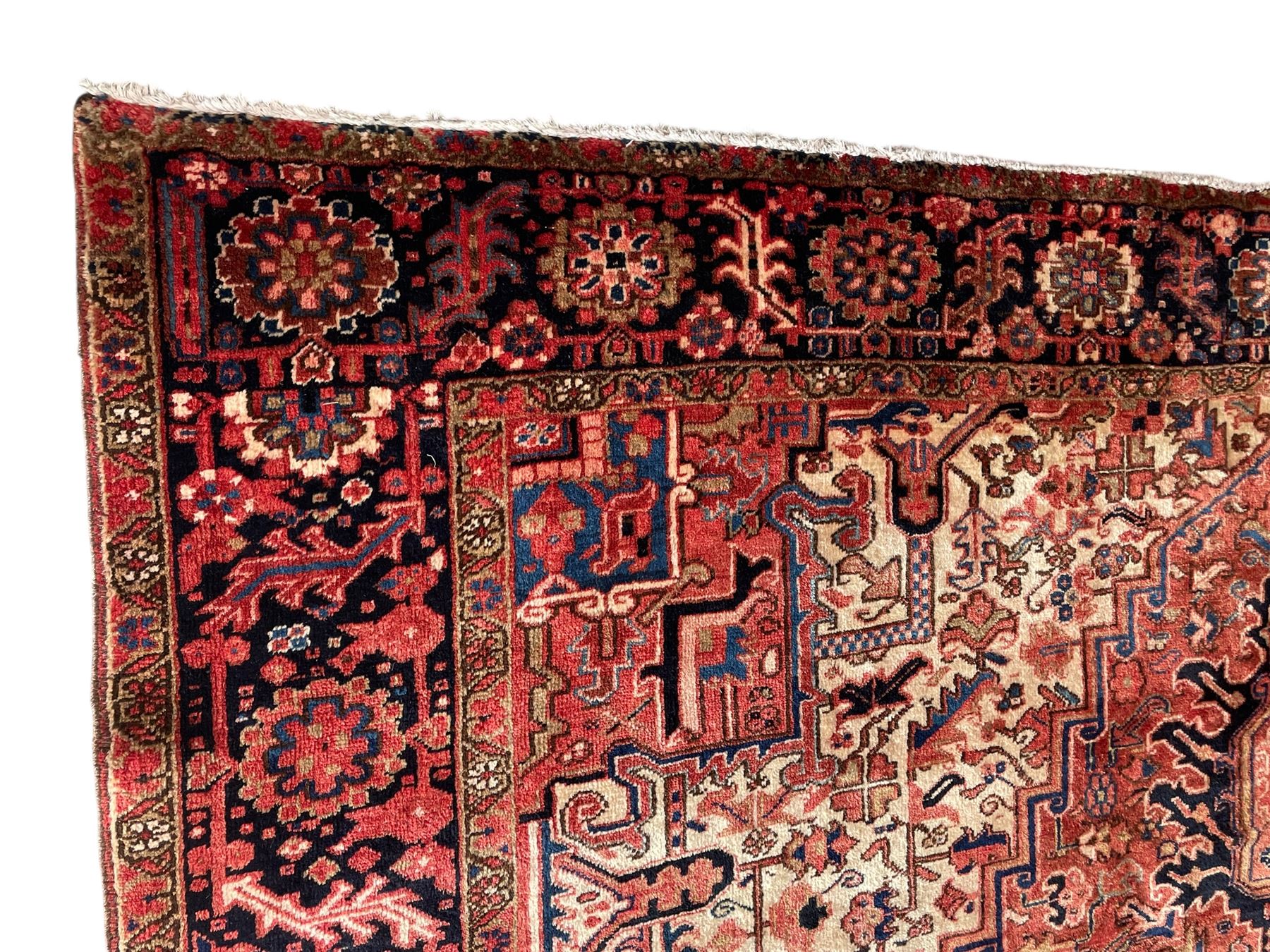 Persian Heriz red ground carpet, large stylised pole medallion surrounded by Pitrak motifs, indigo ground border decorated with stylised flower heads and trailing leafy branches, within floral pattern guard stripes