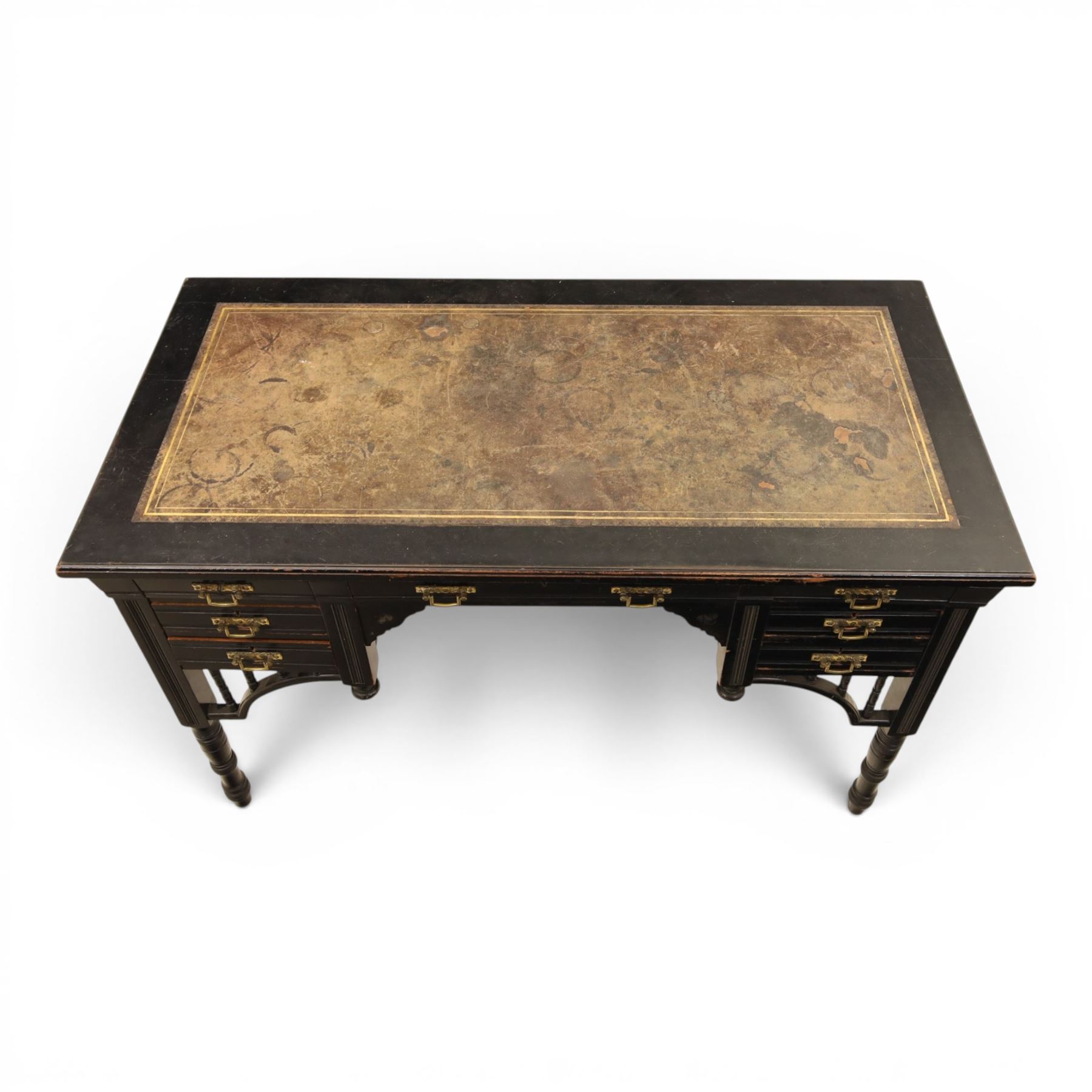 Victorian Aesthetic Movement ebonised writing desk, rectangular top with inset tooled leather, central frieze drawer with pierced spandrels, flanked by two banks of three drawers, brass swing handles, raised on turned supports 
