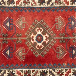 Caucasian Shirvan hand-knotted rug, red madder field with hooked lozenge medallions and stylized motifs, framed by ivory stepped spandrels and multiple geometric borders in indigo brown and ivory, with serrated palmettes and angular devices 
