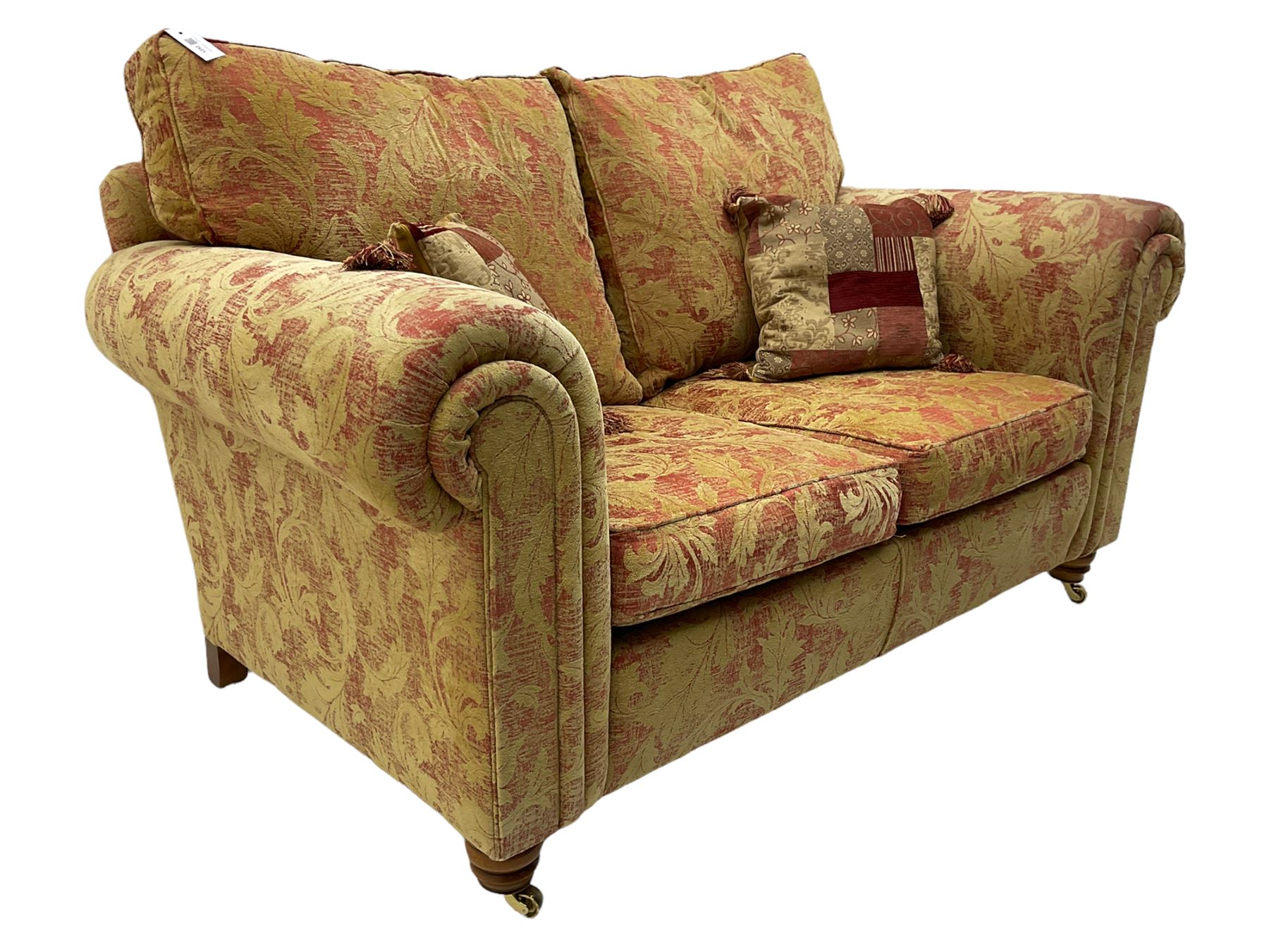 Duresta two seat sofa, upholstered in pale gold and rose fabric, mahogany feet; and matching rectangular footstool