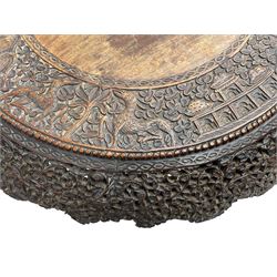 Late 19th century Anglo-Indian carved hardwood occasional table, circular tilt-top carved profusely with mythical animals and foliage decoration, pierced and carved with interlaced leafy branches, leaf carved pedestal supports on a raised platform with further carved and pierced foliage decoration, four carved feet in the form of mythical beasts with gaping jaws 