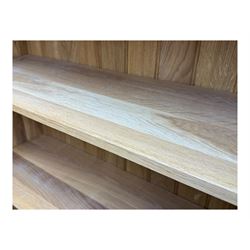 Contemporary light oak open bookcase, rectangular form with projecting top, fitted with five adjustable shelves, on a straight plinth base