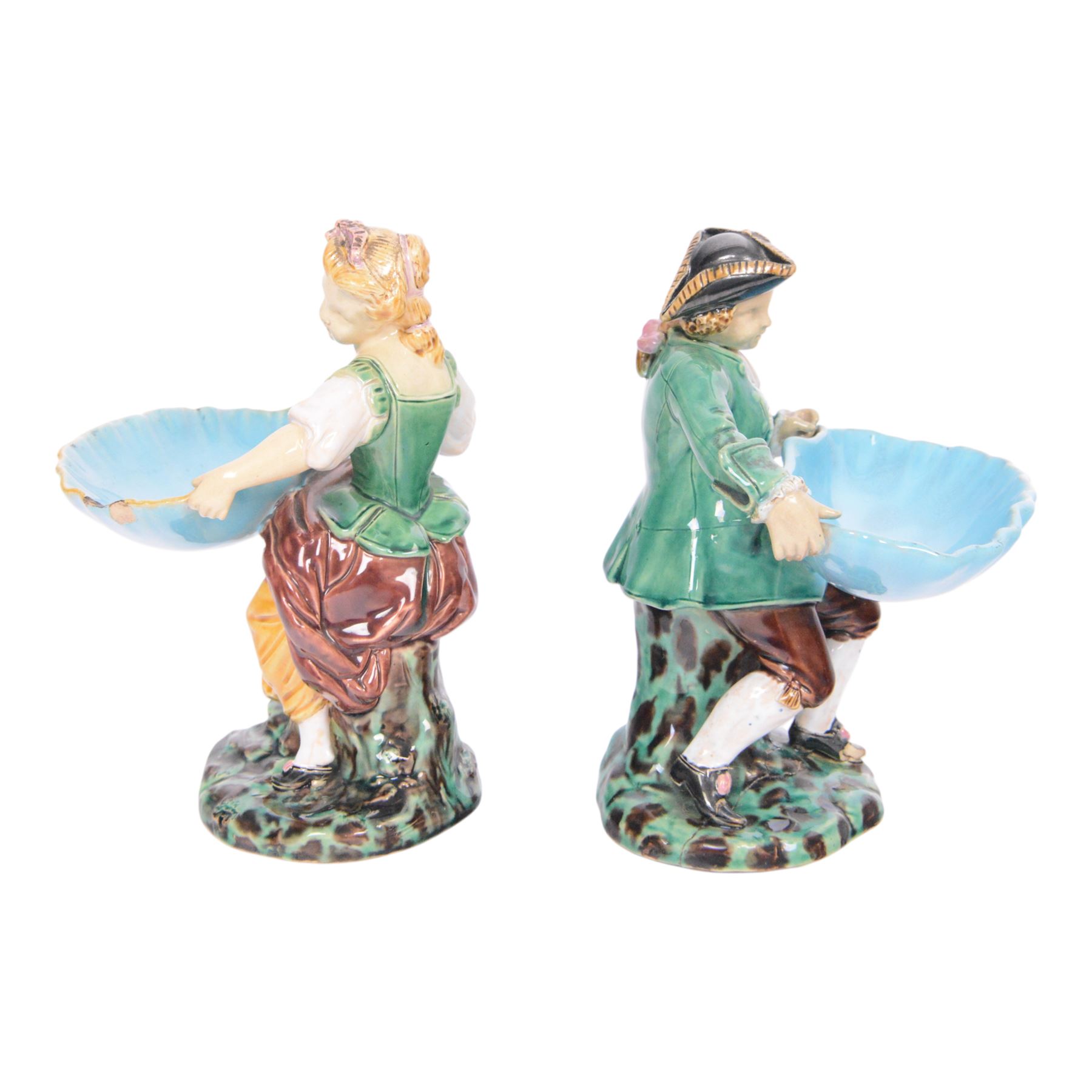 Pair of Minton majolica Hogarth figures, modelled as a seated boy and girl, on tree stumps, both holding sweetmeat dishes, with impressed marks beneath, H18cm 