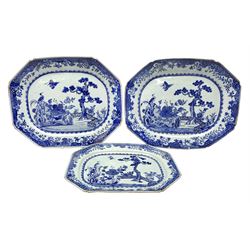 Three late 18th/early 19th century Chinese export blue and white platters, of canted form, decorated with a fenced garden with pine tree, rockwork, peonies, and cranes, within spearhead and cell diaper and foliate borders, larger pair W43cm, smaller example W35.5cm