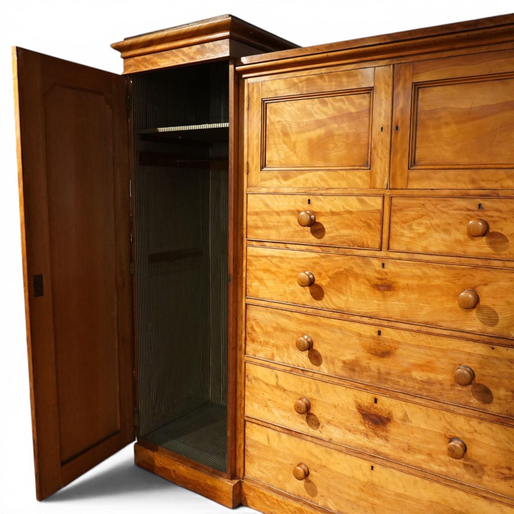 Victorian satinwood reverse breakfront triple wardrobe, projecting moulded cornice over twin full-length panelled cupboard doors flanking central linen press section, fitted with two cupboard doors above two short and four long drawers, turned wooden handles and moulded plinth base