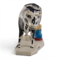 Three Staffordshire cow creamers, one with treacle glaze, the other two painted black and white with a seated figure of a milkmaid, H14cm