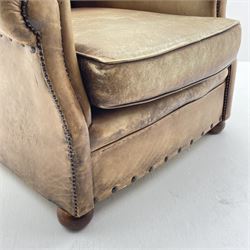 Wing back armchair upholstered in studded tan leather