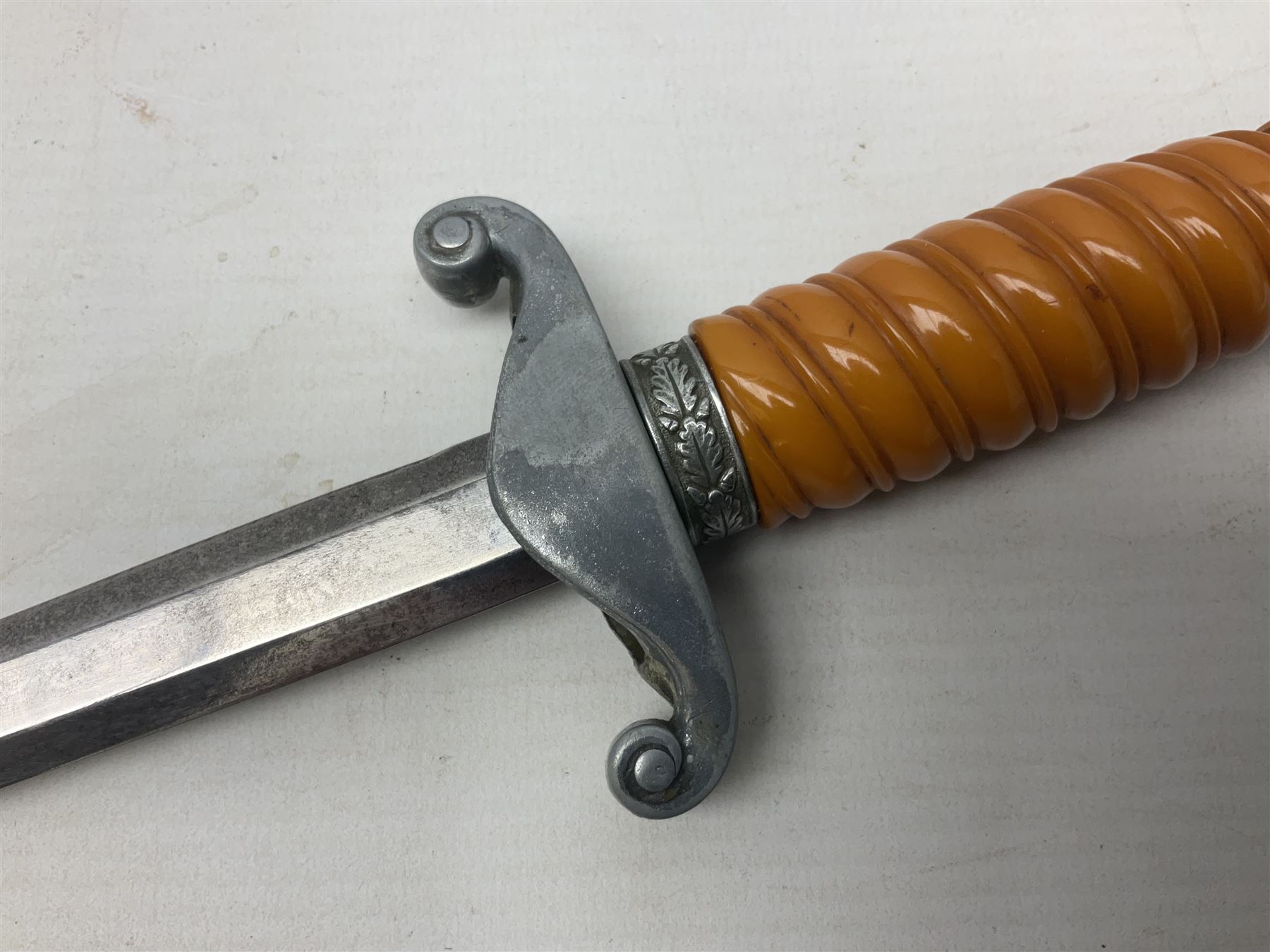 Late WW2 German Army Officers dress dagger, with unmarked 25cm double edged steel blade, orange celluloid grip, pommel and ferrule with oakleaves relief and cross guard with eagle; in original beaded scabbard with two hanging rings L39.5cm overall