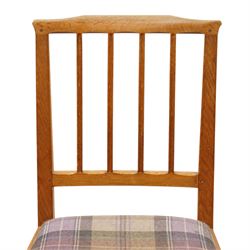 Acorn Industries - set of eight oak dining chairs, the shaped cresting rail over a fluted stick back, the drop-in seats upholstered in contrasting form with four pale mauve and four in purple tartan, raised on square supports, carved with acorn signature, by Alan Grainger, Brandsby