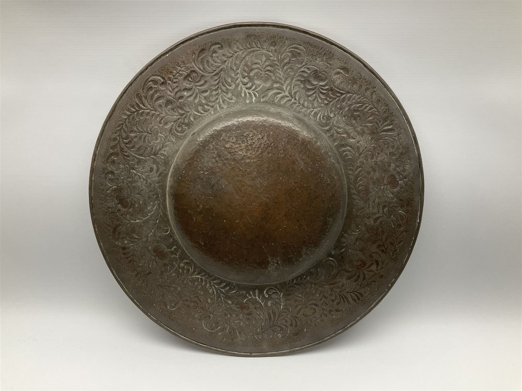 Arts and Crafts Keswick School of Industrial Arts copper charger, decorated with planished centre and repousse scrolling foliate tendrils to rim, D44cm