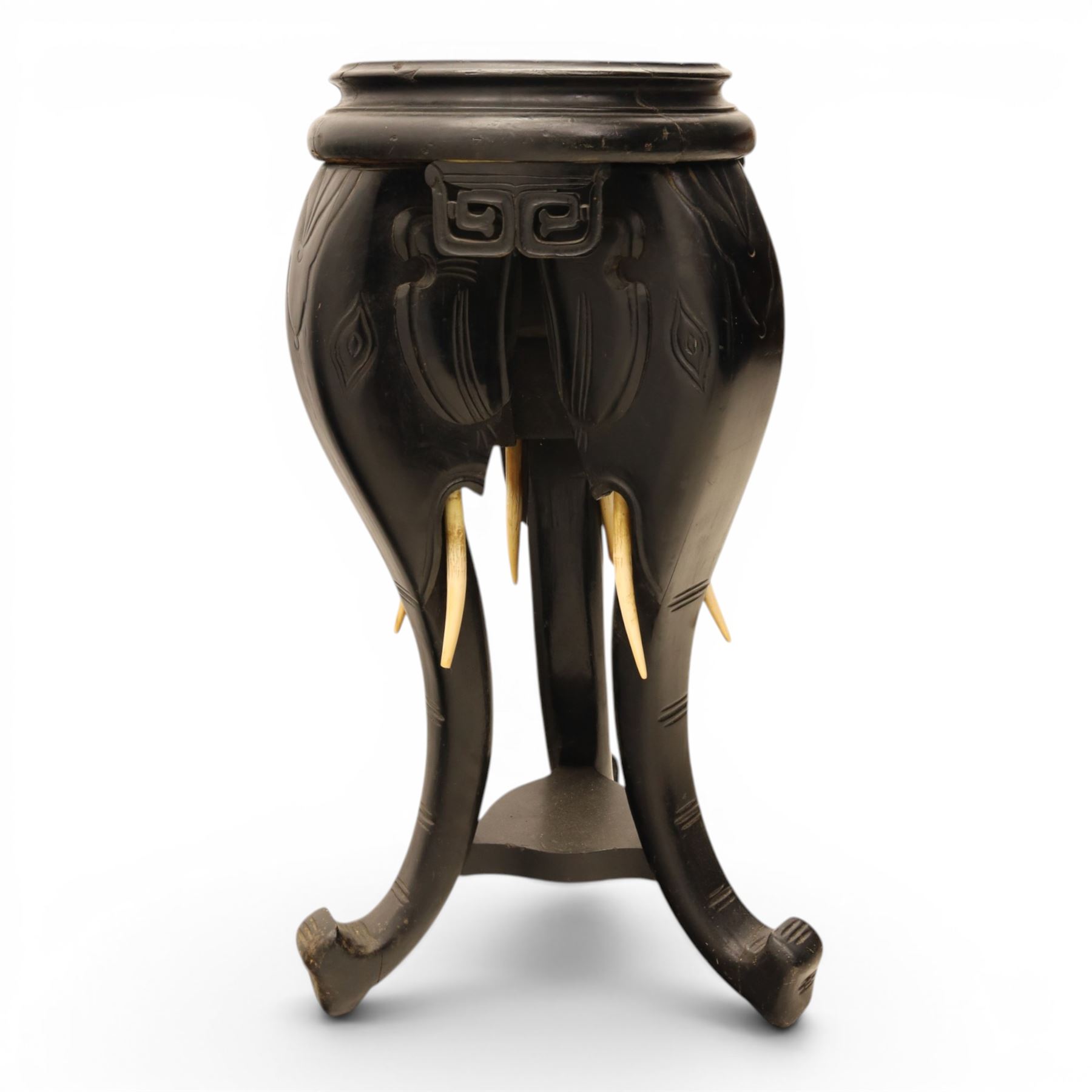 Oriental design black lacquered jardinière stand, circular moulded top with raised rim, the base formed as three elephant heads with carved ears and simulated tusks, on shaped supports with paw terminals
