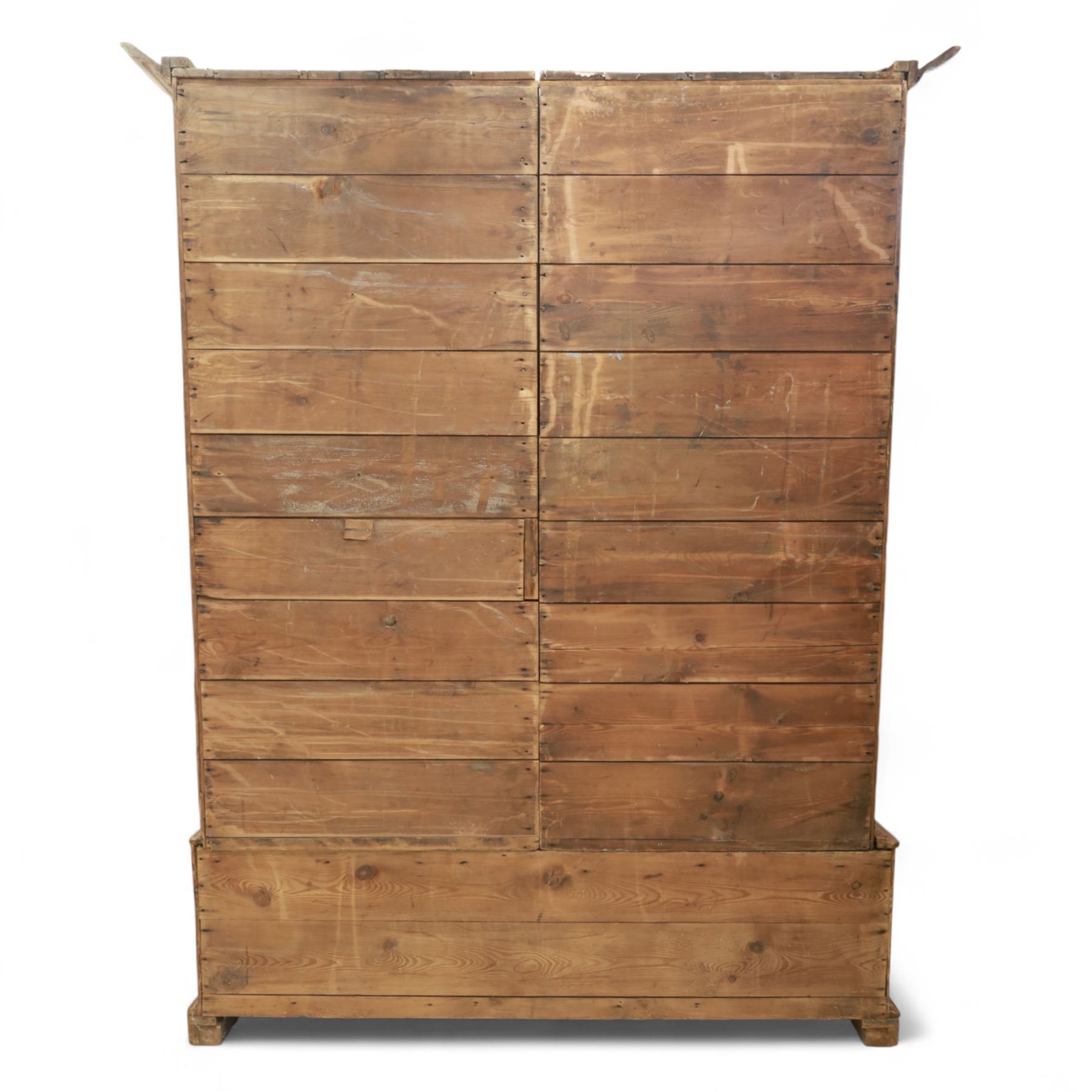 Late 19th century pine wardrobe, with stepped cornice over triple panelled doors, applied foliate carvings to outer panels, raised over a separate pine plinth drawer with moulded facia and twin glass pulls
