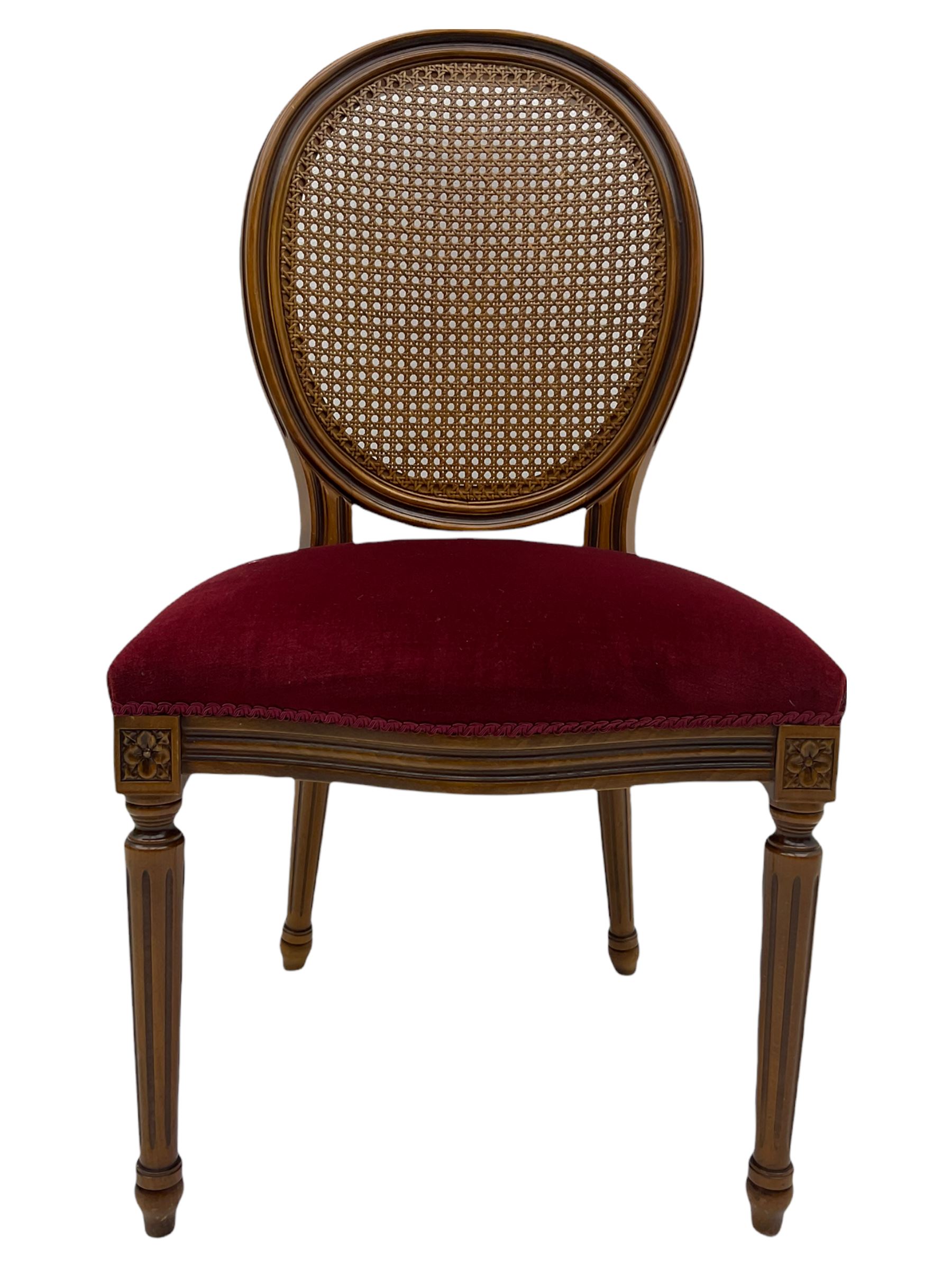 Set six French style walnut finish dining chairs, oval cane bergere backs over serpentine seats upholstered in red, flower head carved fluted supports