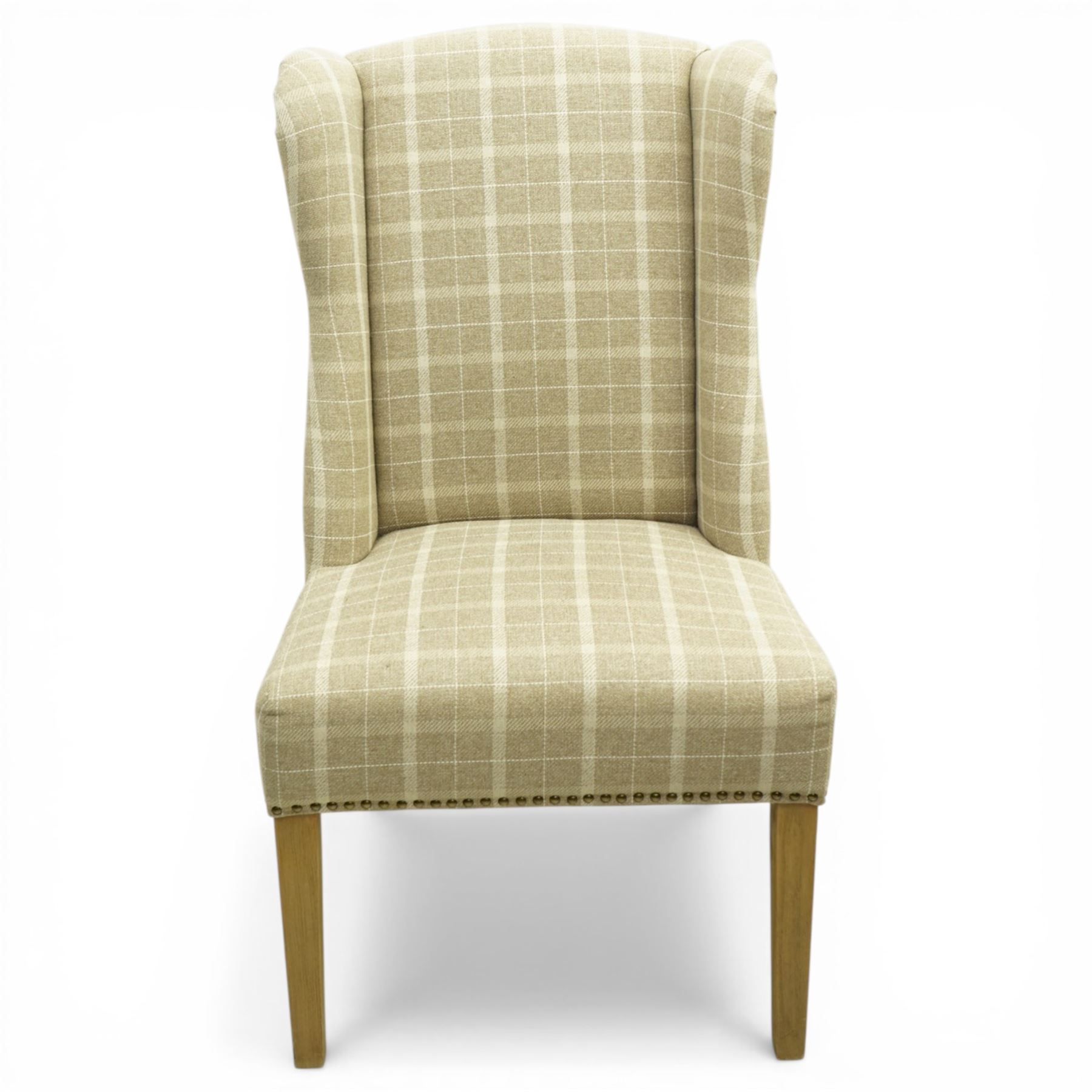 Contemporary wing back dining chair, fully upholstered in beige plaid fabric with studded edge detail, shaped back and seat, raised on tapering supports