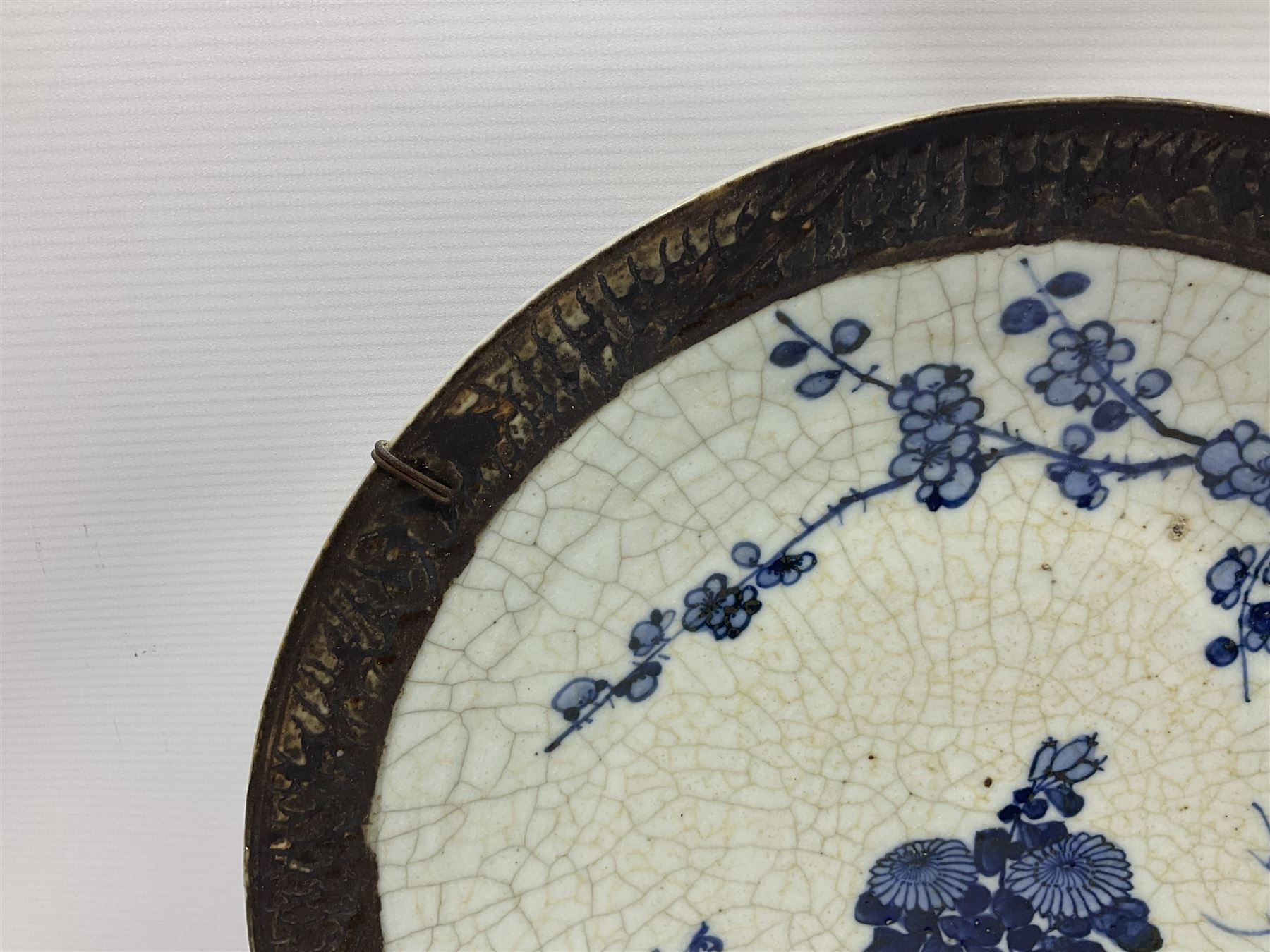 20th century Chinese blue and white crackle glaze charger, decorated with peonies, prunus blossom, and rockwork, within simulated bronze border, with character mark verso, D34cm