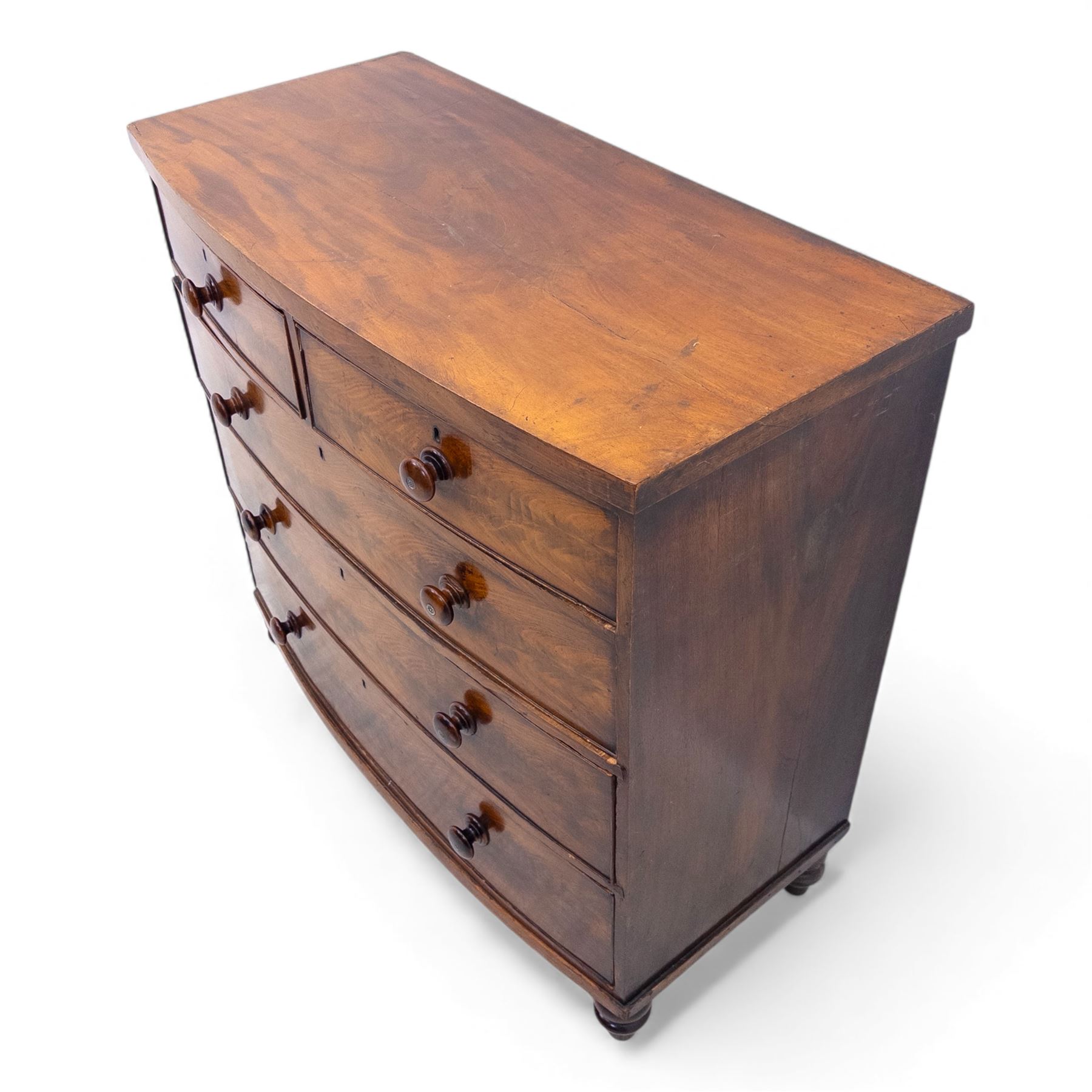 19th century bow front mahogany chest of drawers, rectangular top with moulded edge above an arrangement of two short and three long graduating drawers with turned wooden handles, raised on turned feet