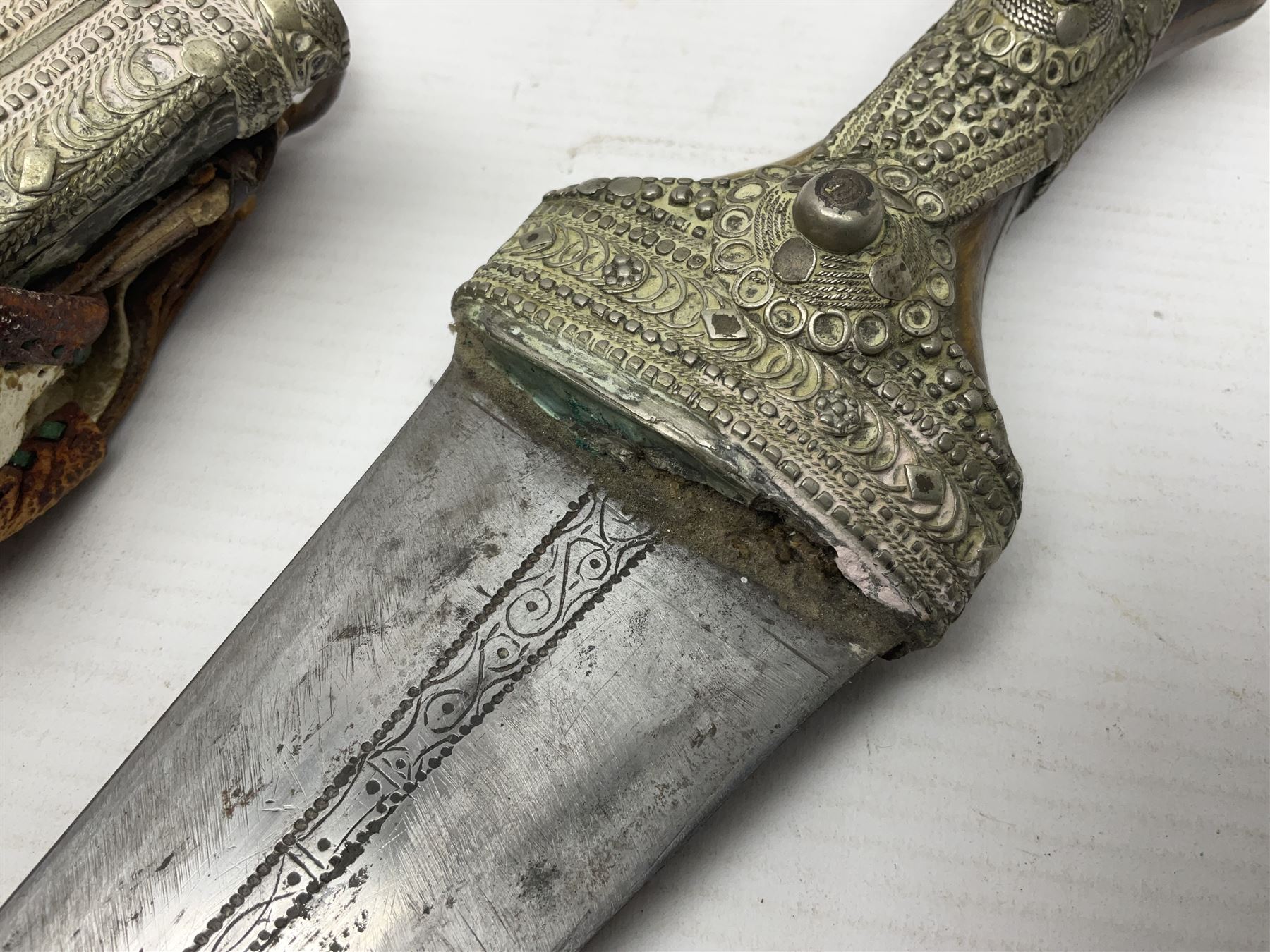 Saudi Arabian khanjar dagger with 29.5cm curving double edged  steel blade; white metal and copper mounted horn grip; in white metal mounted brass and leather scabbard incorporating embroidered leather wearing strap