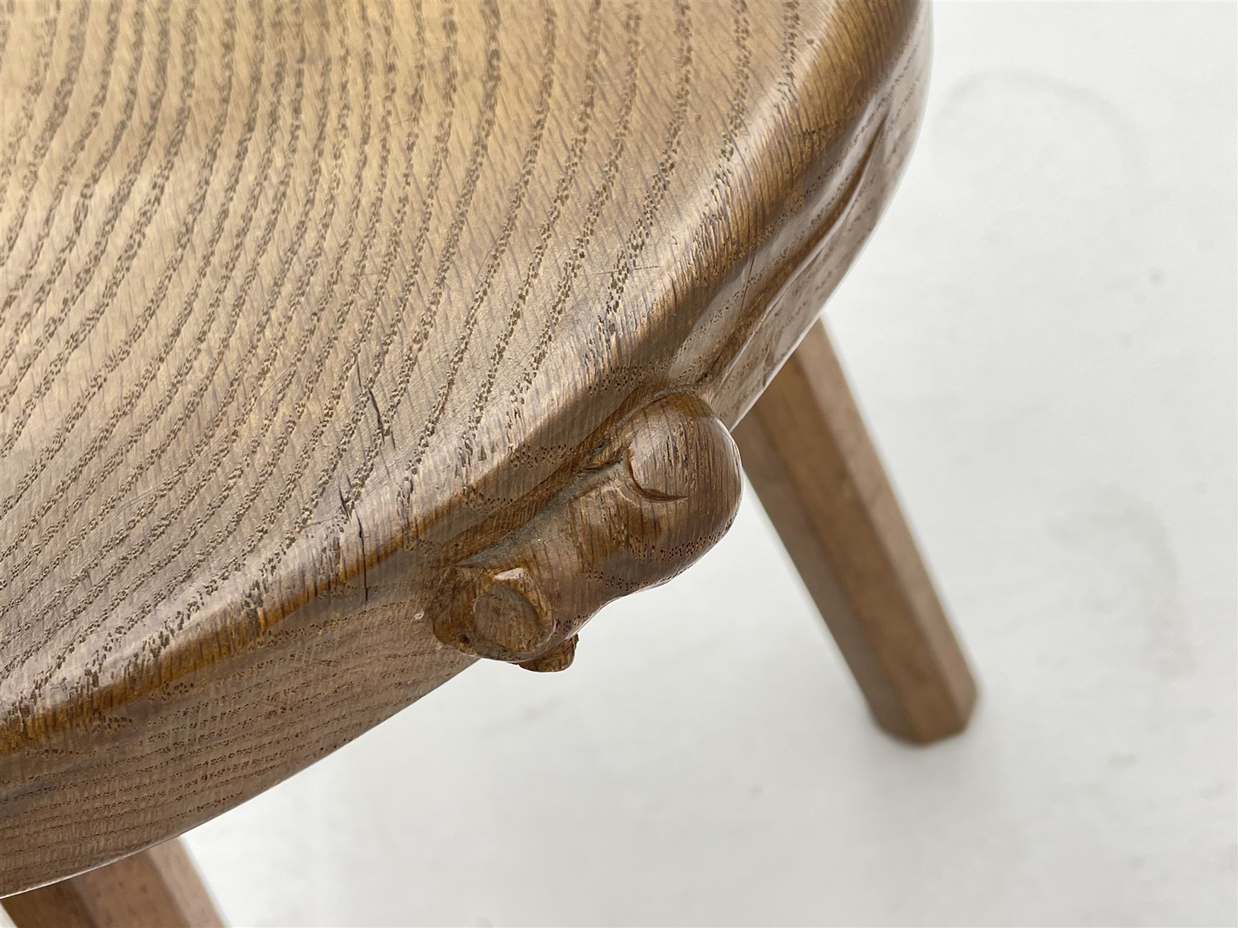 'Mouseman' oak three legged stool with dished kidney shaped seat, tapered octagonal supports, with carved mouse signature, by Robert Thompson of Kilburn 