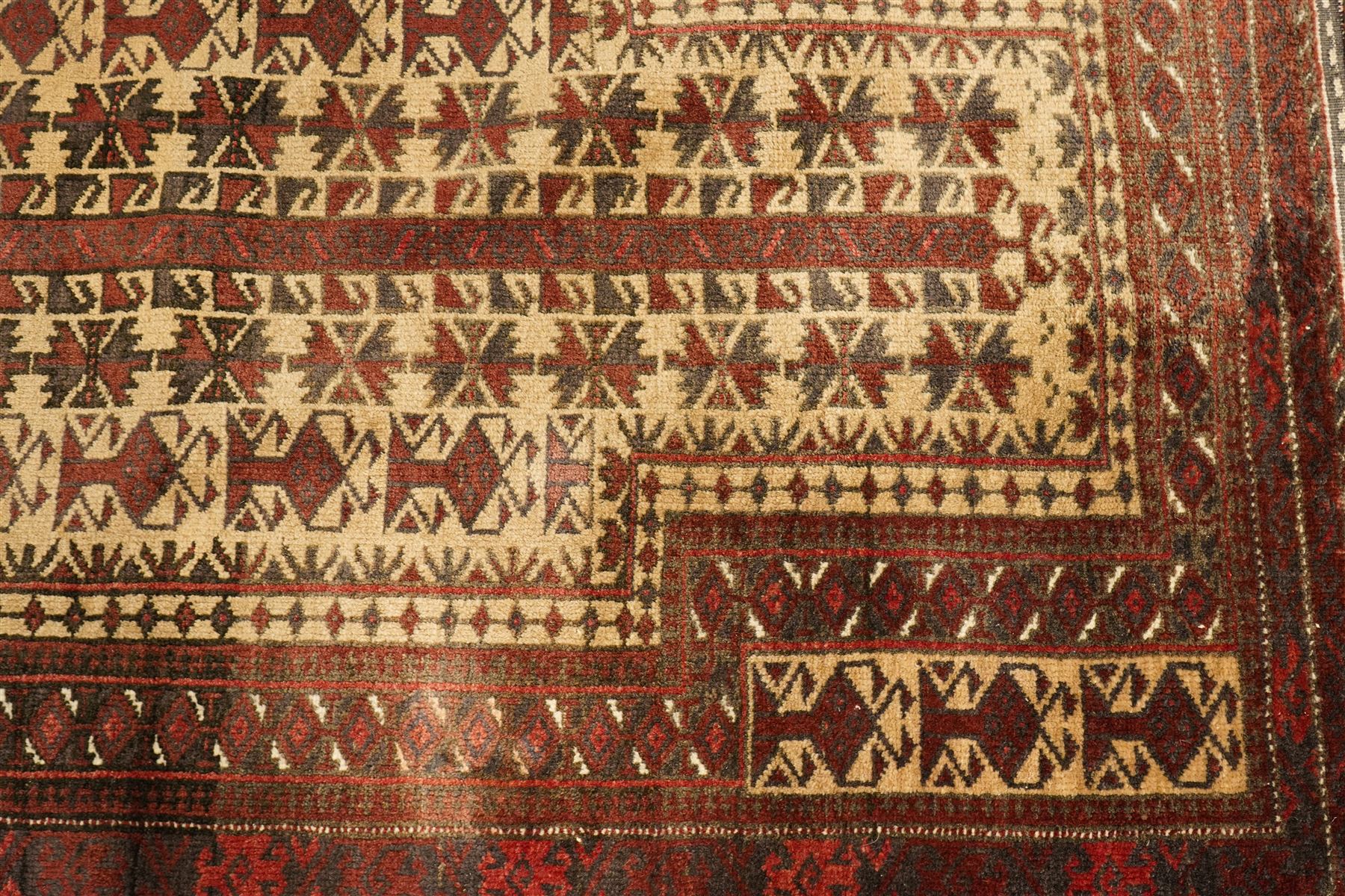 Two hand-knotted rugs, comprising Persian runner and Turkoman prayer rug, Persian hand-knotted runner, red and dark navy ground with four diamond medallions and geometric motifs, enclosed by multicoloured geometric border, striped kilim ends with fringes, H244cm, W58cm; Turkoman hand-knotted prayer rug, ivory mihrab field decorated with repeating stylised geometric motifs, enclosed by multiple geometric borders in madder red and brown, with fringed ends, H150cm, W93cm