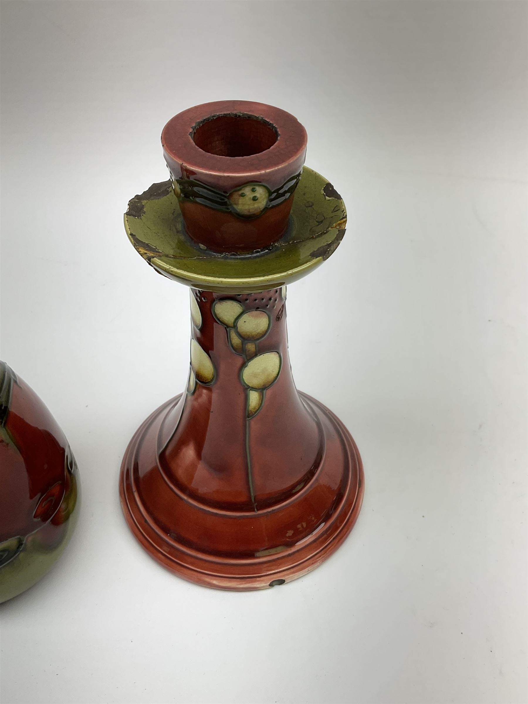 Minton Secessionist vase, with tube-lined stylised flower head decoration upon a red and green ground, printed mark to base 'Minton Ltd, No. 31', together with a matching pair of Minton Secessionist candle sticks, candlestick H17cm