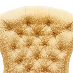 Victorian Aesthetic Movement walnut framed nursing chair, the fan back and sprung seat upholstered in buttoned foliate patterned gold damask fabric with fringing, raised on beaded tapering fluted supports with ceramic castors