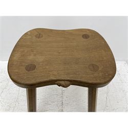 'Mouseman' oak four-legged stool, shaped and dished top carved with mouse signature on four tapered octagonal splayed supports, by Robert Thompson of Kilburn 