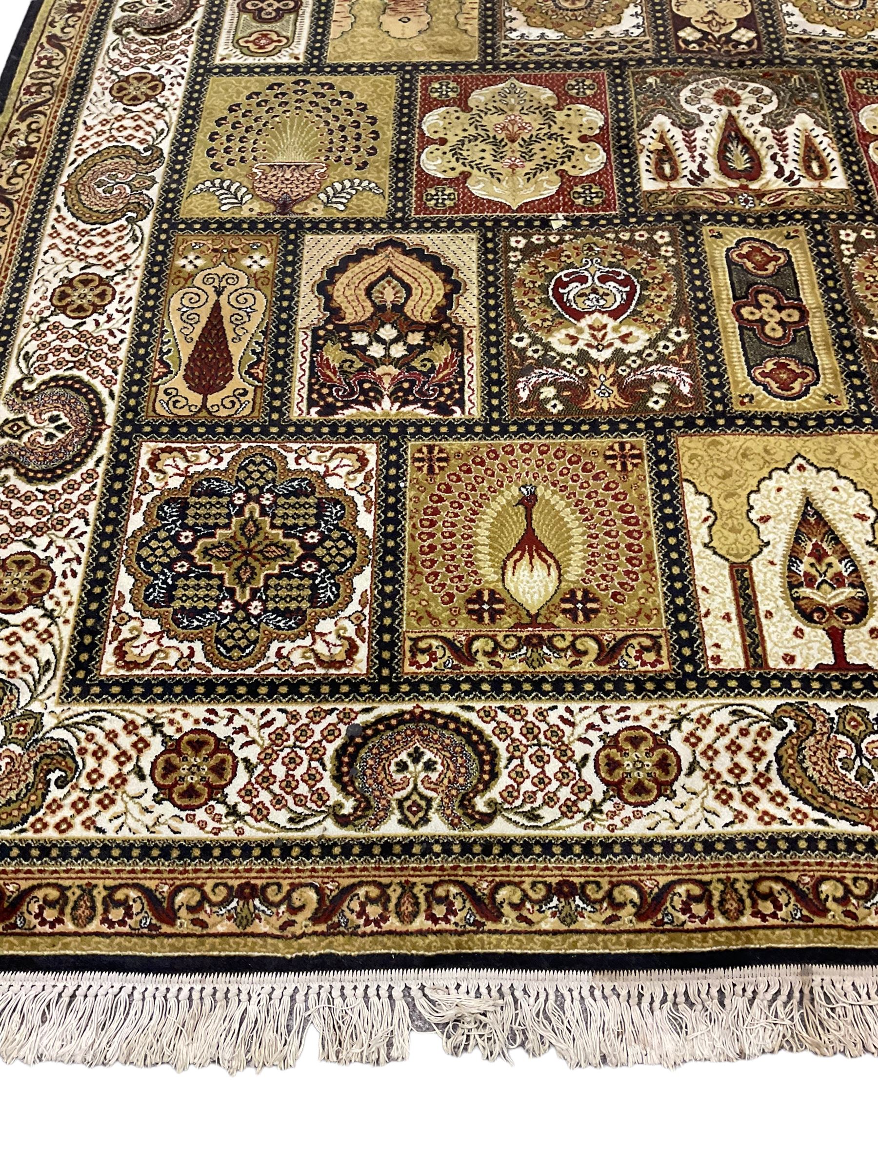 Persian design carpet, the field with various size tiles decorated with stylised plant motifs, floral urns and peacocks, the main border decorated with repeating foliate motifs and trailing flower heads