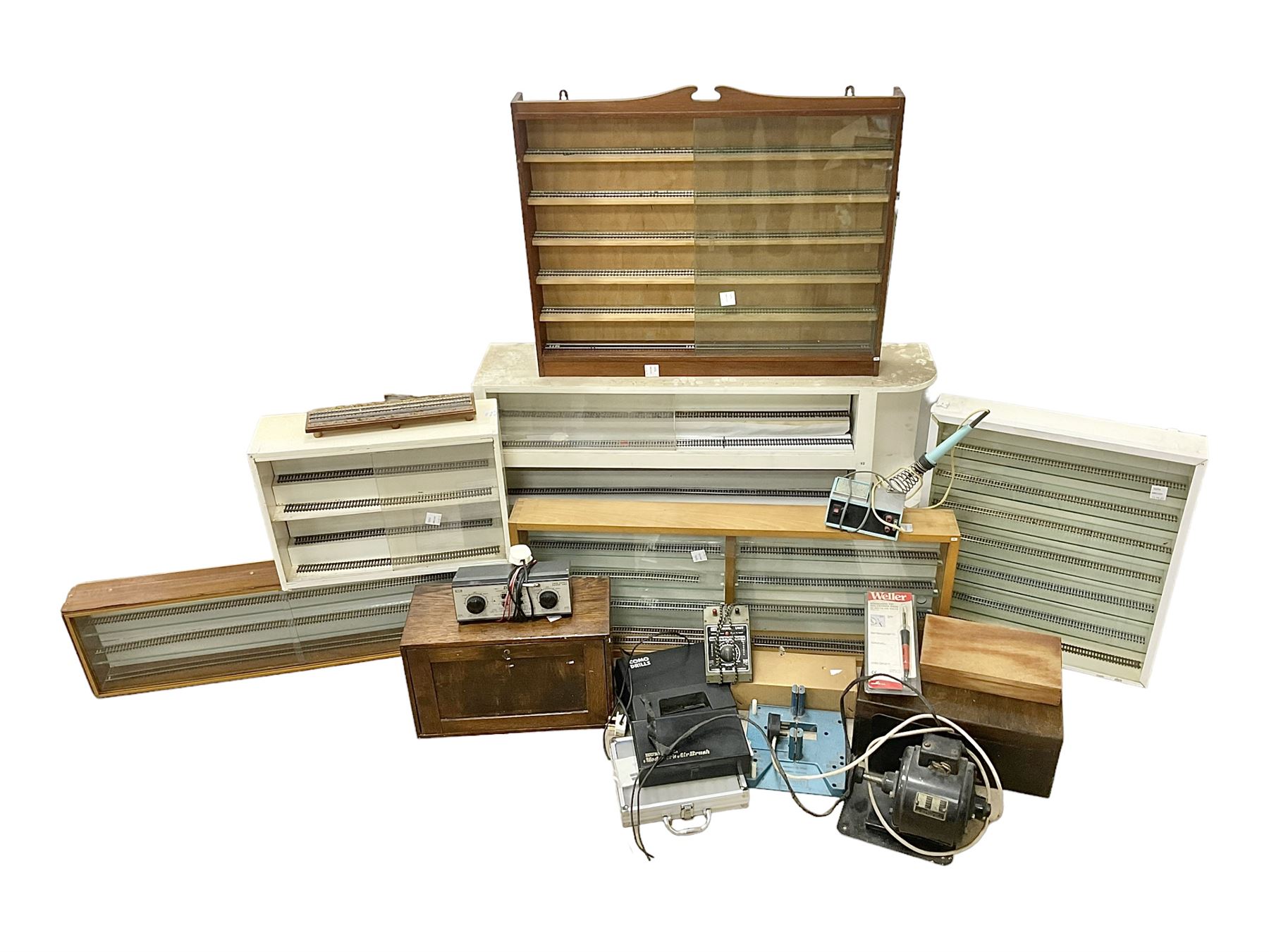 Six shelved cabinets for displaying ‘00’ gauge locomotives comprising plain plywood and white painted examples with track applied to various shelves, largest H63cm, W107cm, D27cm; Collection of tools for building model locomotives to include Weller PU-2D Soldering Pencil and Standard Tip Soldering Iron 20W/230V, Humbrol Modellers Airbrush, Power Supply Units and two wooden chests one of which housing a collection of tools including tweezers, scalping tools, wrenches etc 