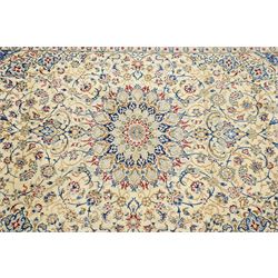 Central Persian Nain hand-knotted carpet, ivory field with central finely drawn cusped medallion of radiating palmette and arabesque form with scrolling vine work, flowering tendrils and stylized foliate motifs in a palette of pale blue, indigo, crimson and sage accents, spandrels of conforming design enclosing intricate floral sprays and arabesques within  multiple borders and narrow guard stripes, with cotton fringe ends 