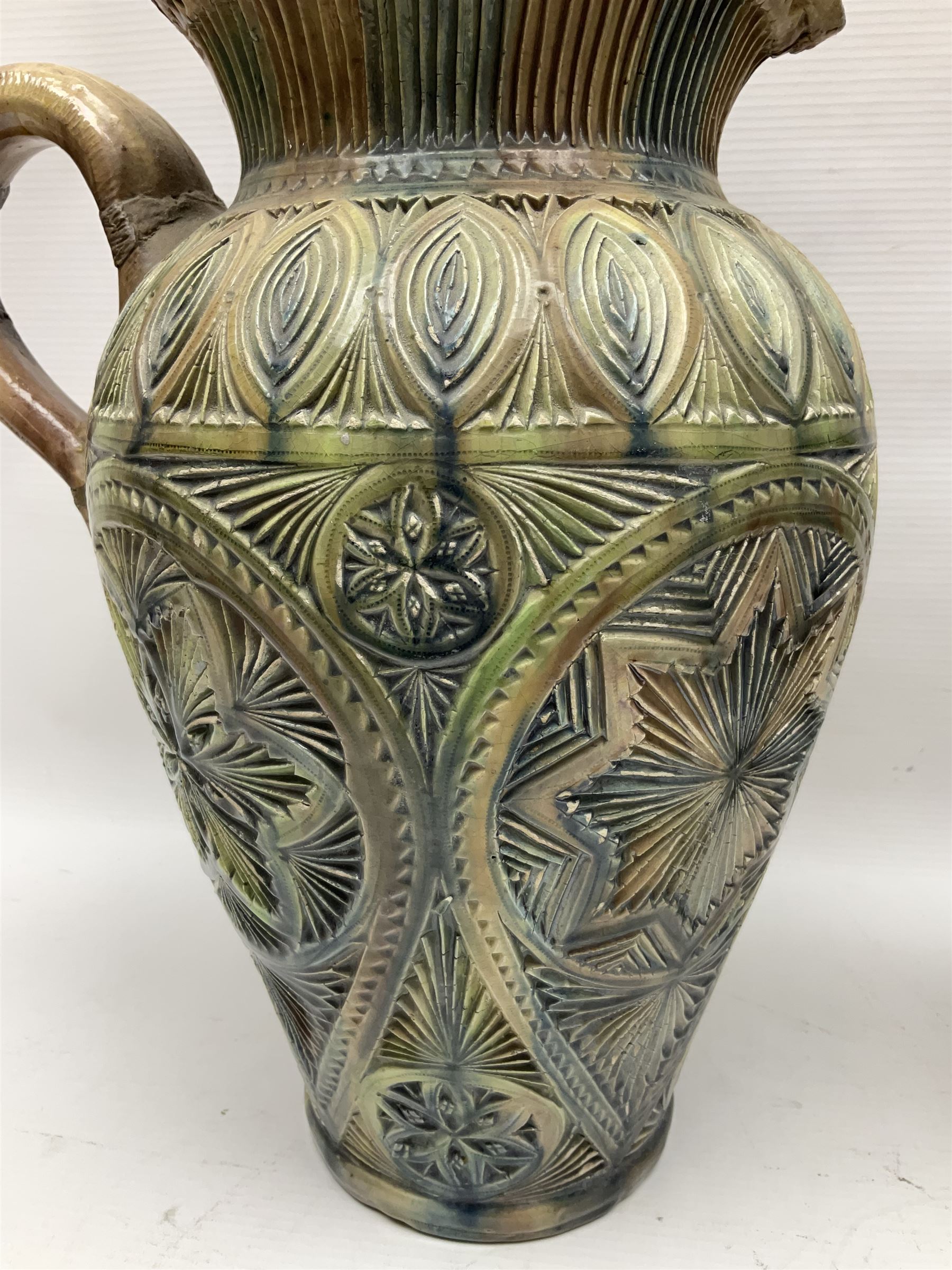 Early 20th century Royal Doulton stoneware vase, decorated with a stylized floral design below a wavy rim, monogrammed B.N, possibly for Bessie Newbery, H28cm, together with an early 20th century glazed jug, heavily carved throughout (2)